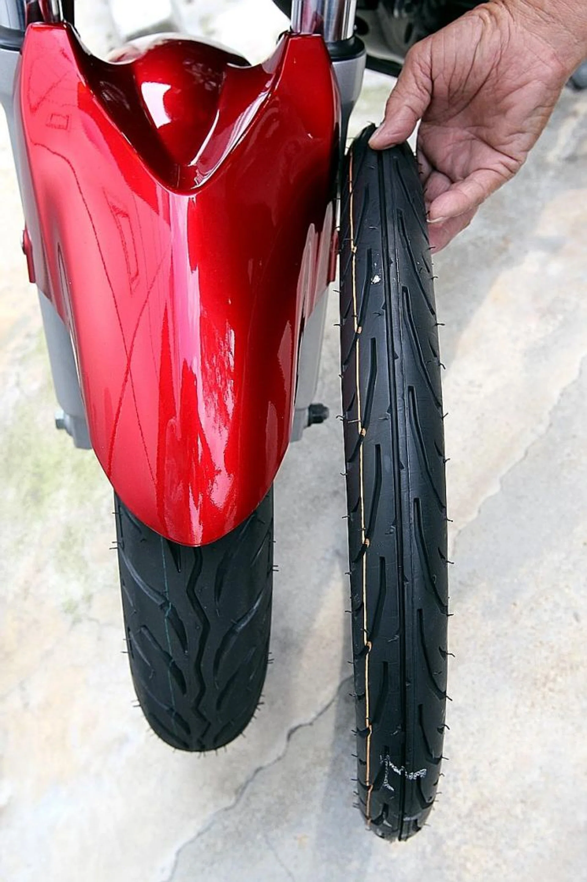 SIDE-BY-SIDE COMPARISON: A standard front tyre (on the motorcycle) compared to an uninflated skinny tyre called sotong.