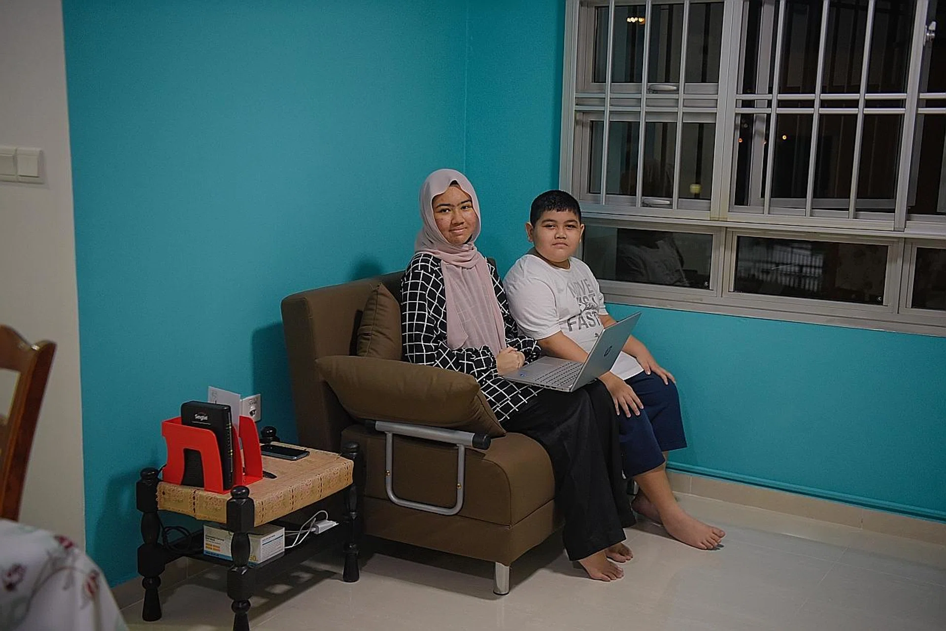 Miss Nur Fatin Hidayah and her brother Muhamad Iman Hakim with the new laptop given by the HEB-Ashram Halfway House. The family also had their house repainted and old appliances replaced.