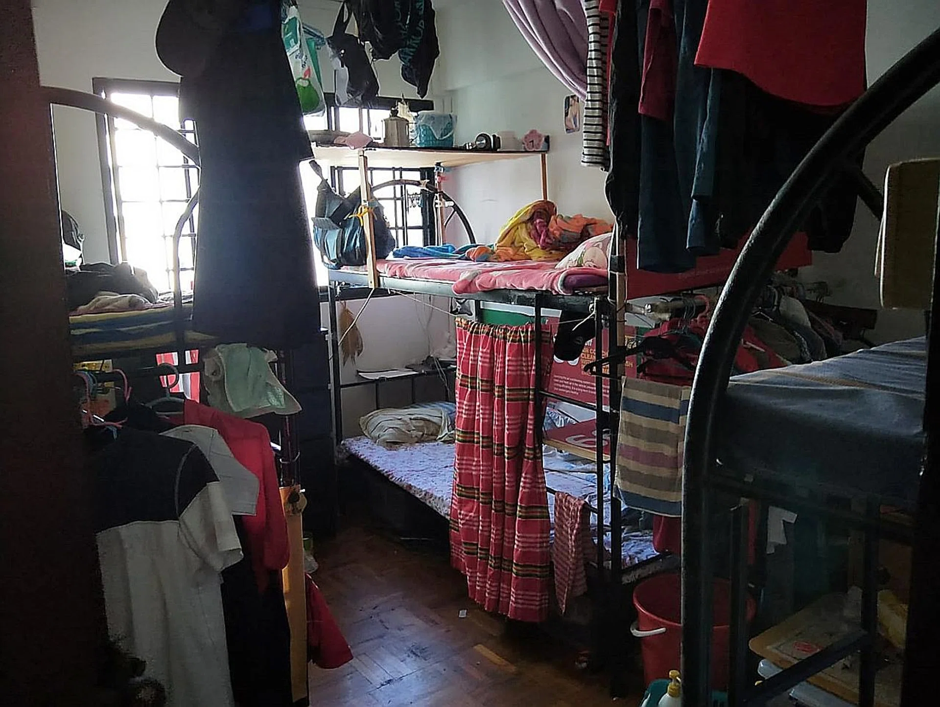 Clothing hang haphazardly from the beds and ceiling. 