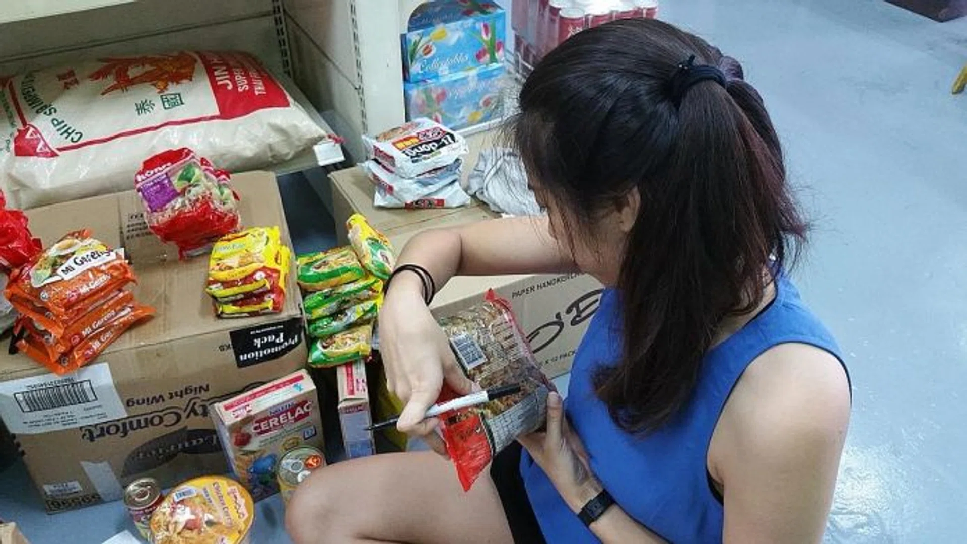GOOD CAUSE: (Above) The staff members at The Food Bank Singapore add labels to items to give them a generic look. This gives products and brands equal opportunity to  be tested by consumers at same prices.
