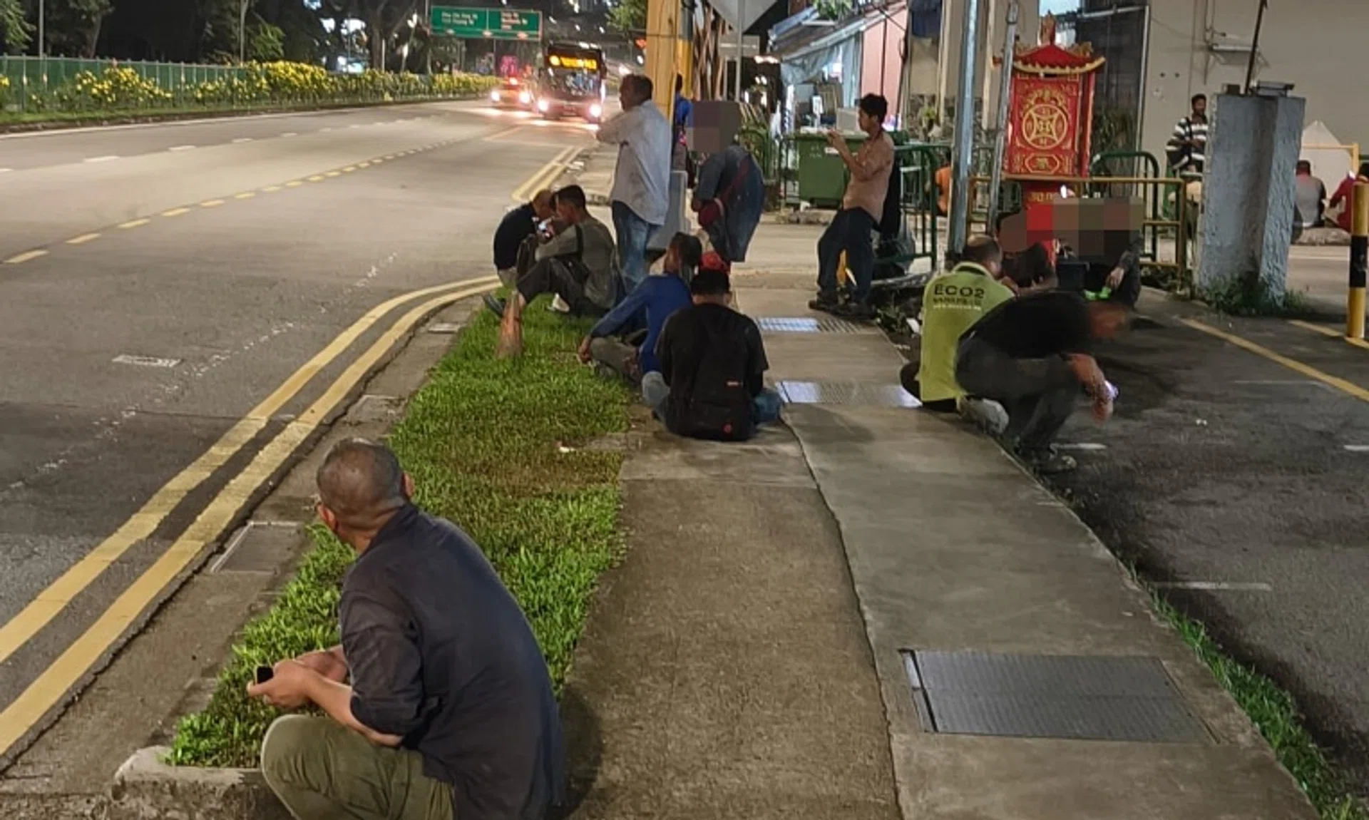 Migrant workers sitting on kerbs close to fast-moving traffic outside a construction site In Upper Bukit Timah Road.