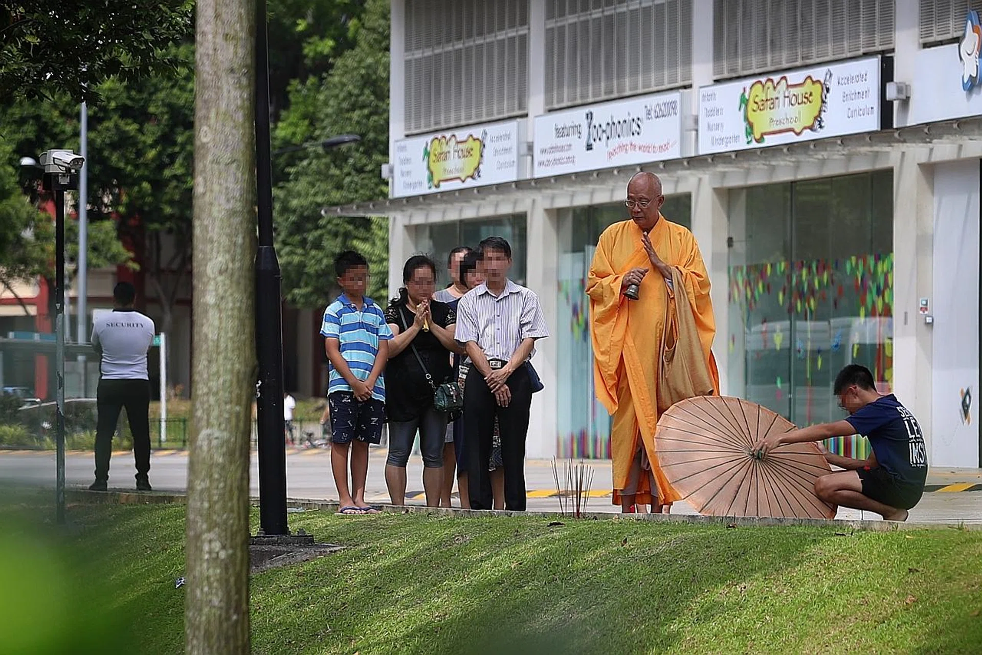 The boy's family observing a priest performing rites near the Woodlands Close building where the tragedy occurred.