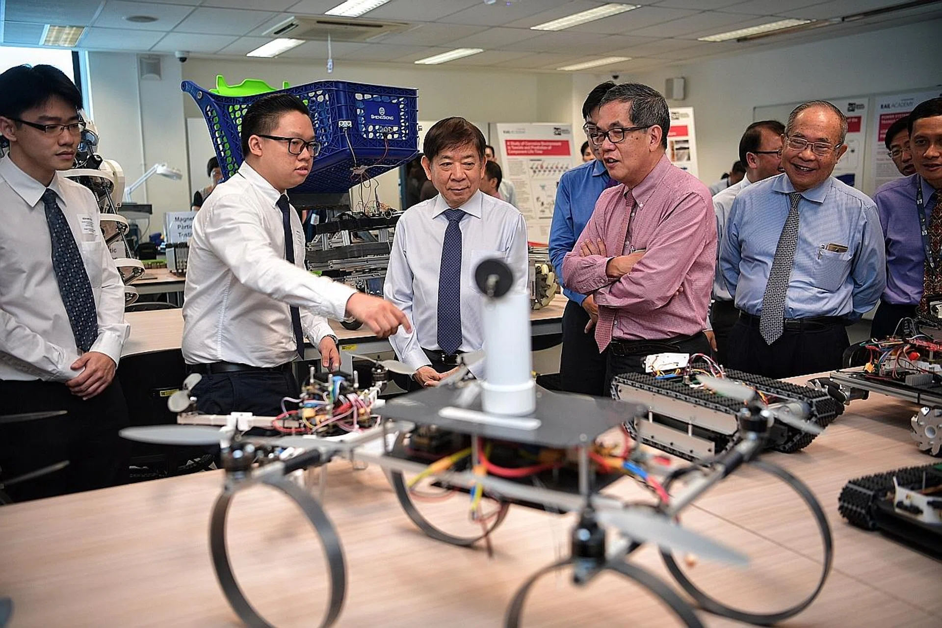 Second-year engineering student Samuel Tan (second from left) shows Transport Minister Khaw Boon Wan (middle) a series of student prototypes at the Singapore Rail Academy. 