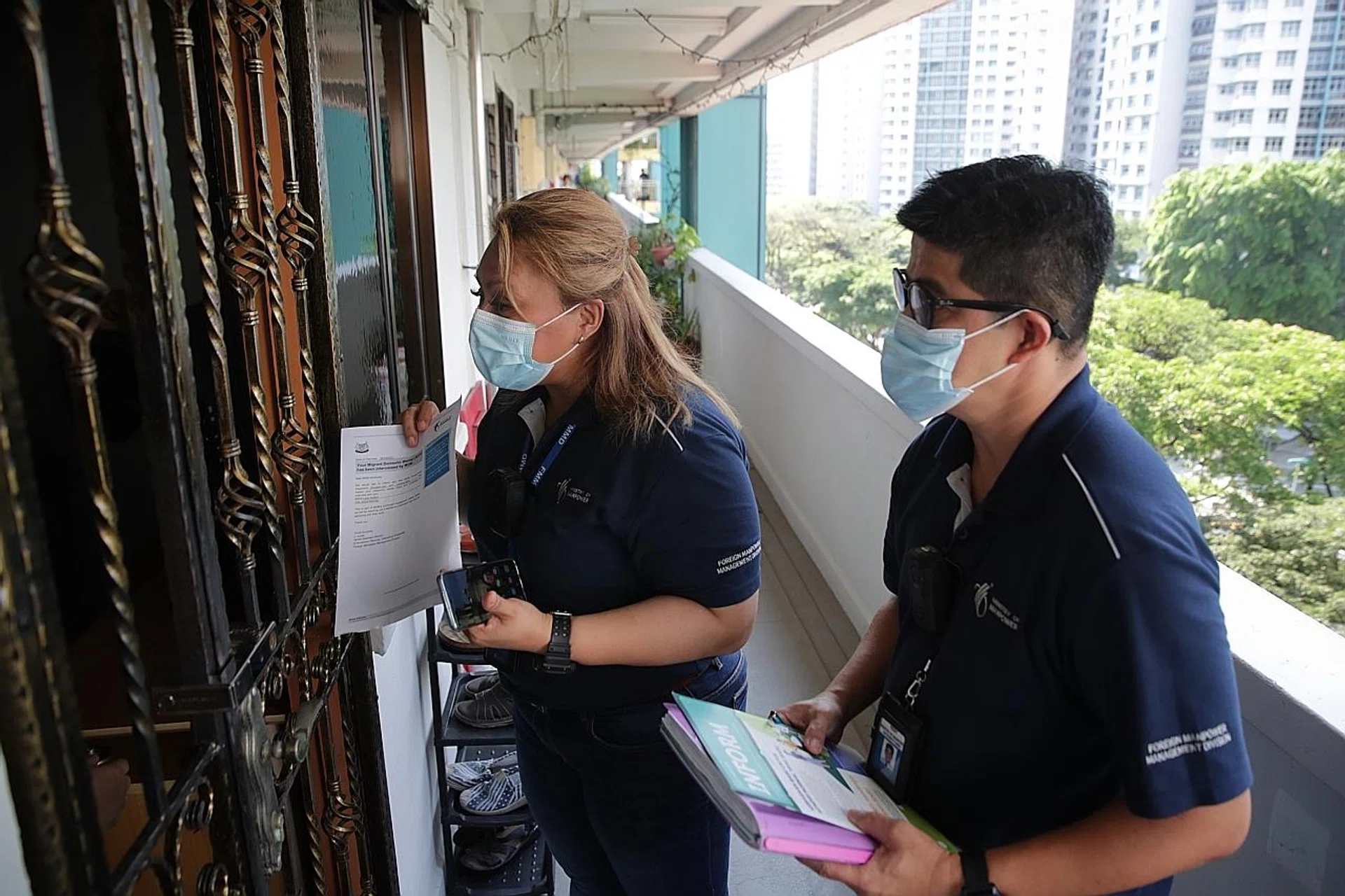 Officers appointed by the Ministry of Manpower speaking to a maid during a house visit in Boon Keng yesterday.