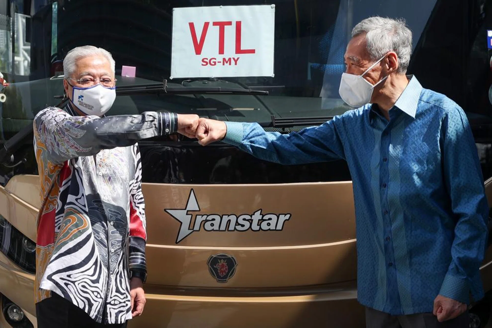 PM Lee Hsien Loong exchanging fist bumps with his Malaysian counterpart Ismail Sabri Yaakob in front of a cross-border bus at Woodlands Checkpoint yesterday.
