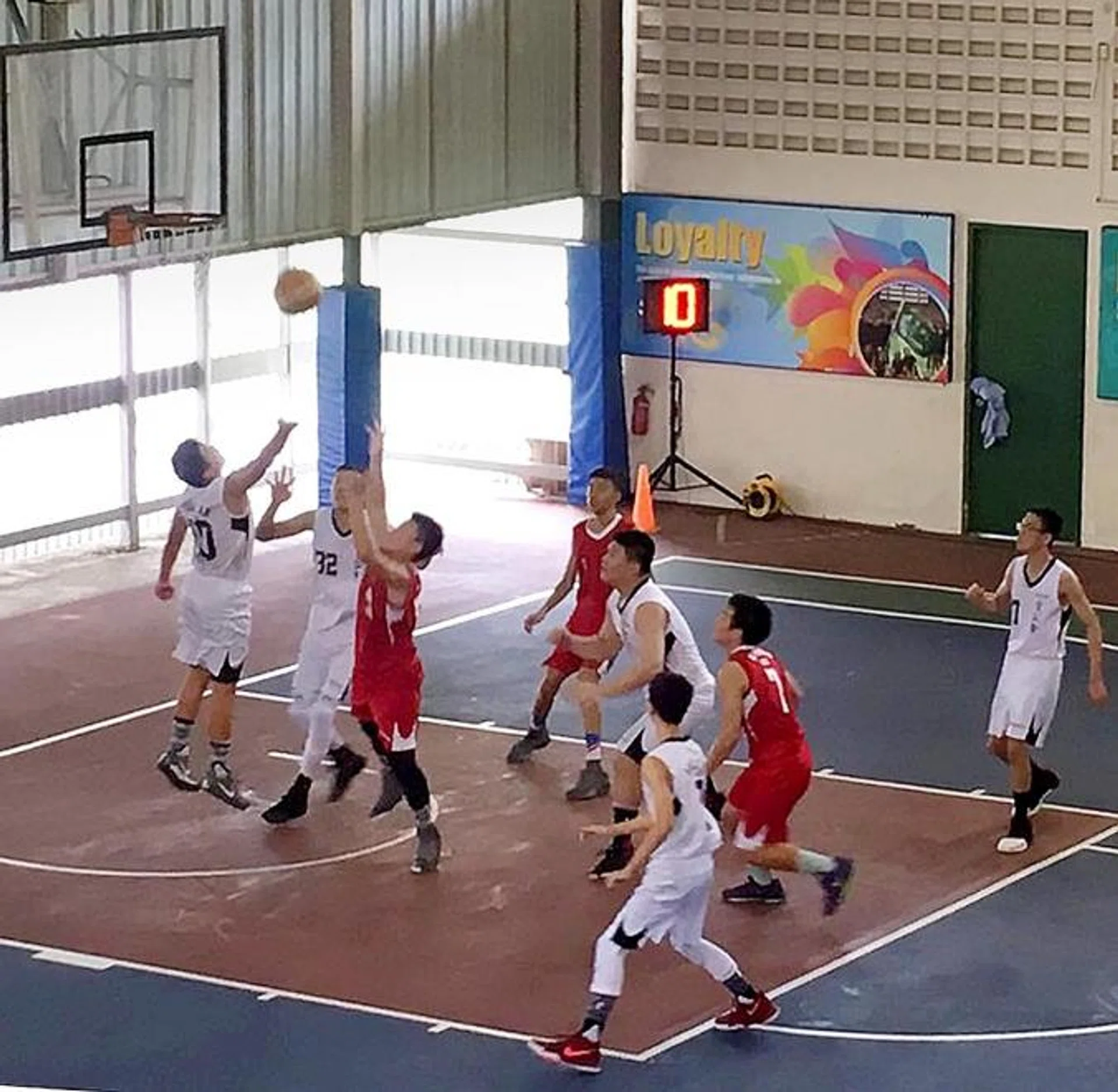 Two Anglican High players (in white) tussling with a Dunman Secondary School player for the ball.