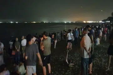 Singaporeans throw trash into the sea to trigger blue waves at Changi Beach