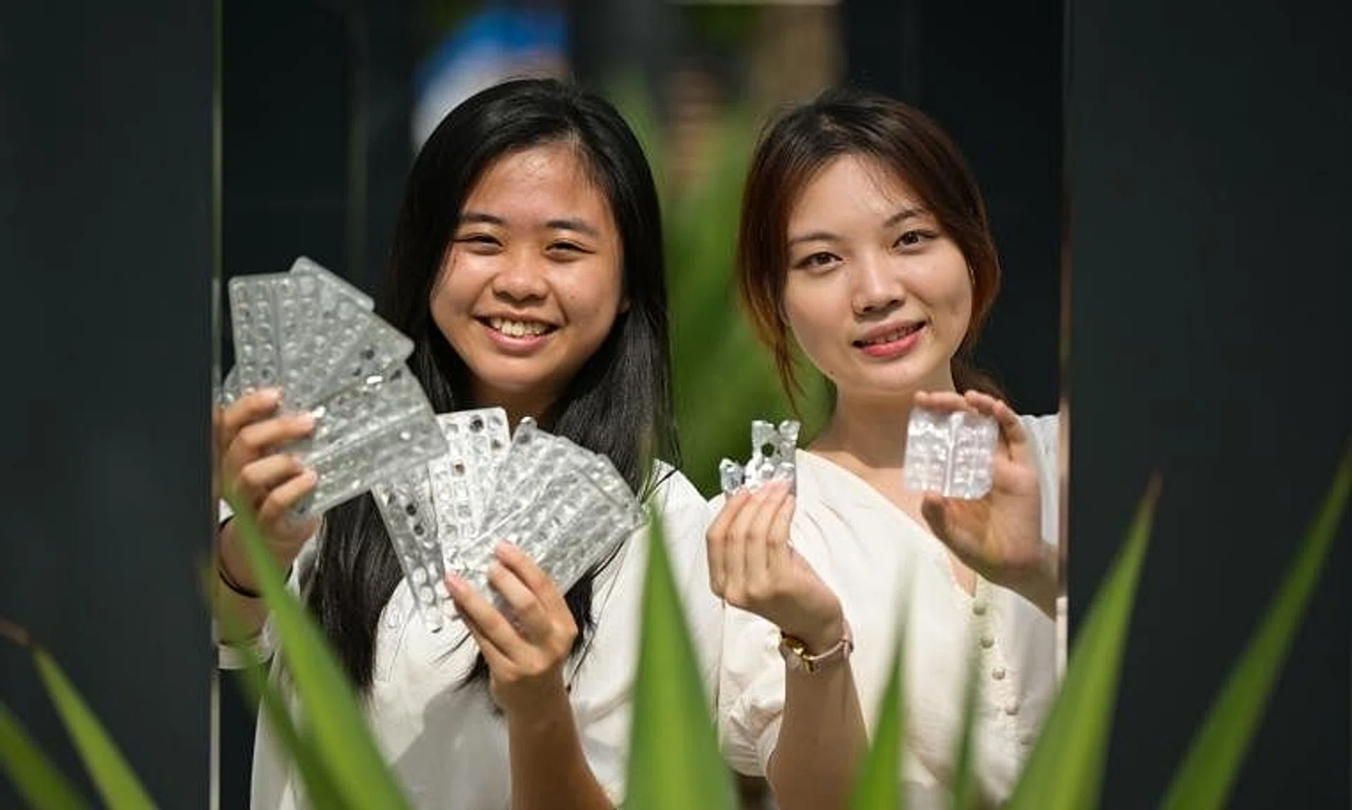 Ms Su Yee Shien (left) and Ms Sophia Ding Ning Ke holding medical blister packaging and recovered aluminium and plastic polymer pieces. 