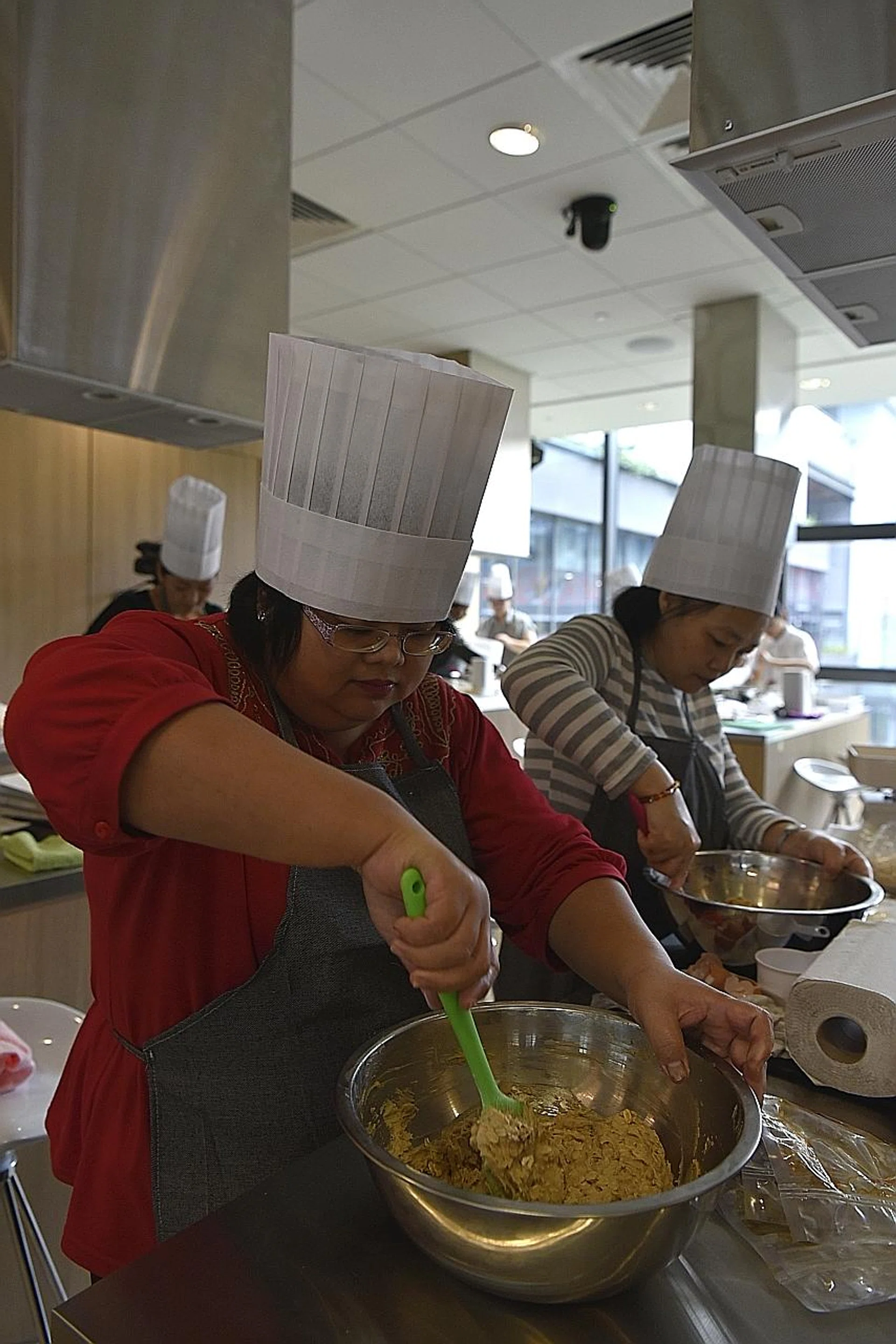 Madam Lau Li Na (in red) and Madam Wang Jia Yuan learning to bake CNY cookies at the class. 