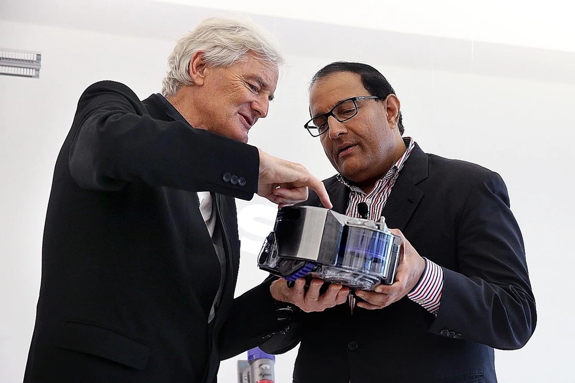 Sir James Dyson (left) shows Minister for Trade and Industry (Industry) S. Iswaran the Dyson 360 Eye robot vacuum cleaner.