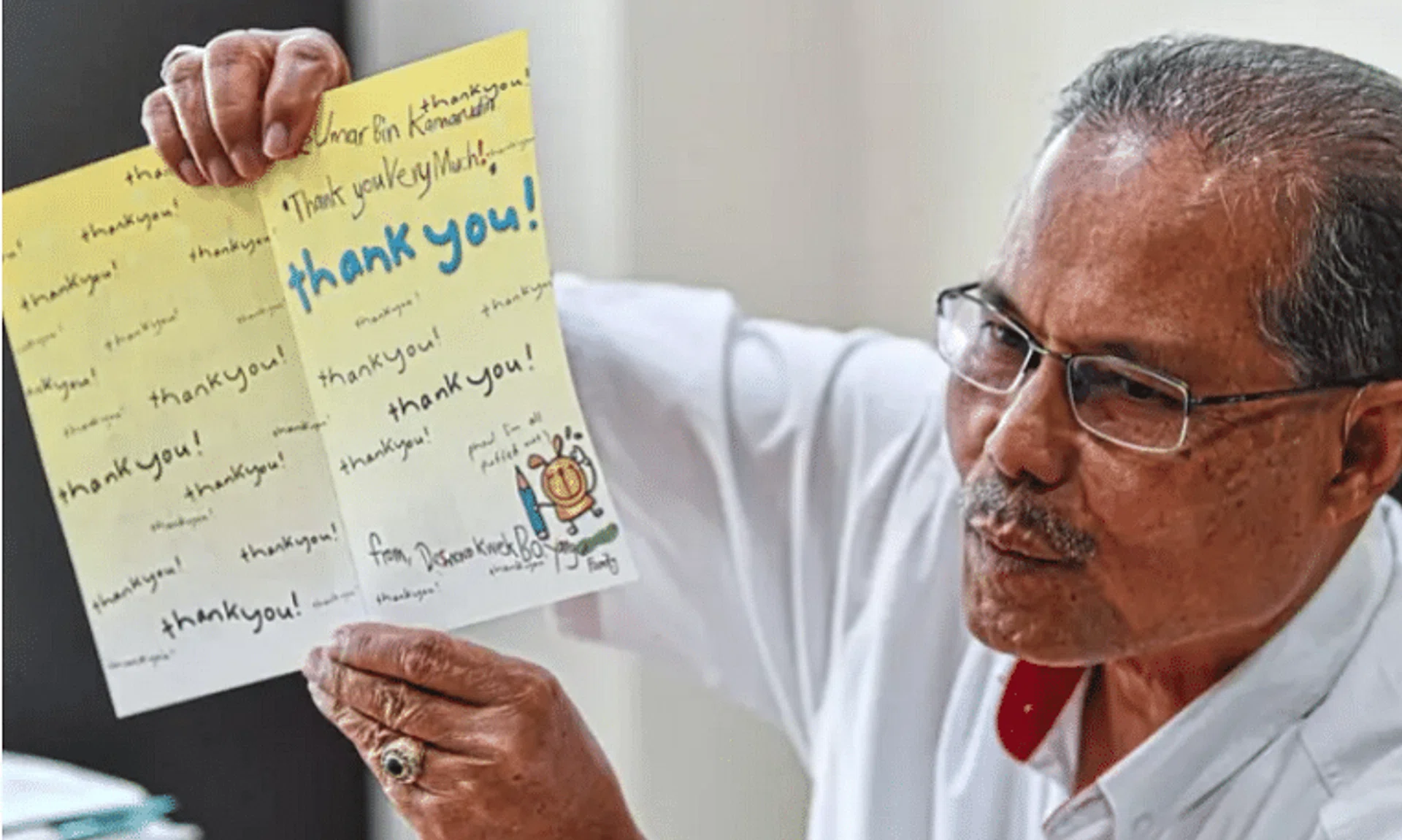 Mr Umar showing the thank-you card given to him nearly 20 years ago by the family of the boy he saved. 