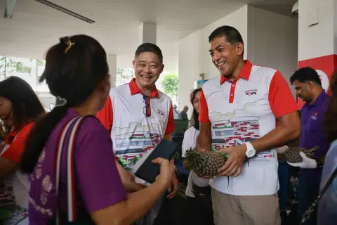Ang Mo Kio GRC MP Darryl David (right) distributing fruits and vegetables to residents on March 29.