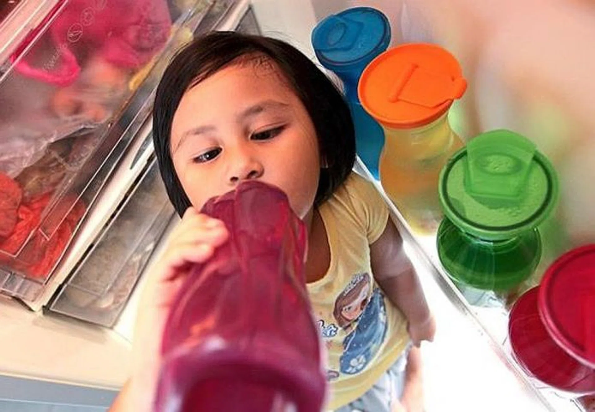 FEELING THE HEAT: Five-year-old Aisyah Zahra drinking cold water ﻿to ﻿while standing in front of the ﻿refrigerator﻿.