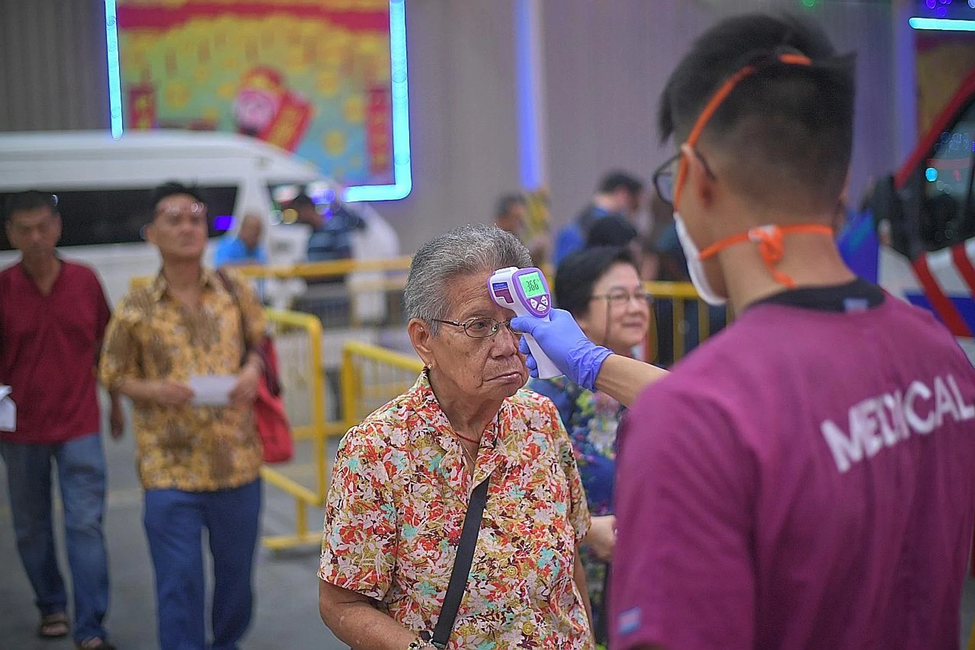 Medical staff from Singapore Ambulance Association engaged by the Loyang Tua Pek Kong temple taking the temperature of visitors before they enter the temple .TNP FILE PHOTO