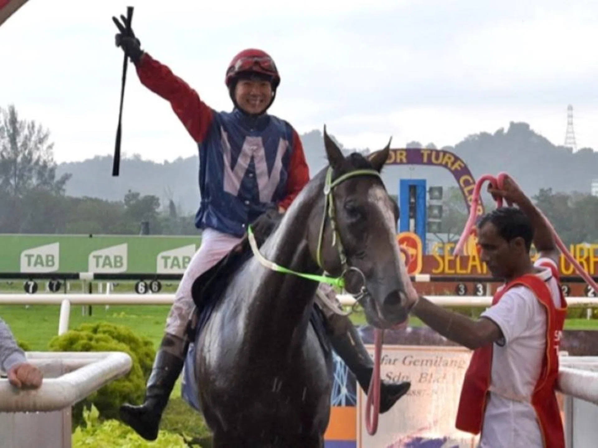 Heavy rain does not dampen Jerlyn Seow's mood as she salutes to her victory aboard Commander for trainer Simon Dunderdale at the Sungai Besi winner's circle on Dec 8.
