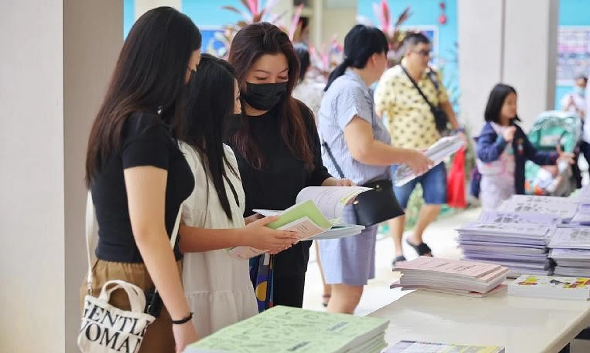 Madam Pauline Fong (third from left) and her daughters browsing assessment books at a CDAC event at Nanyang Junior College on Dec 3.