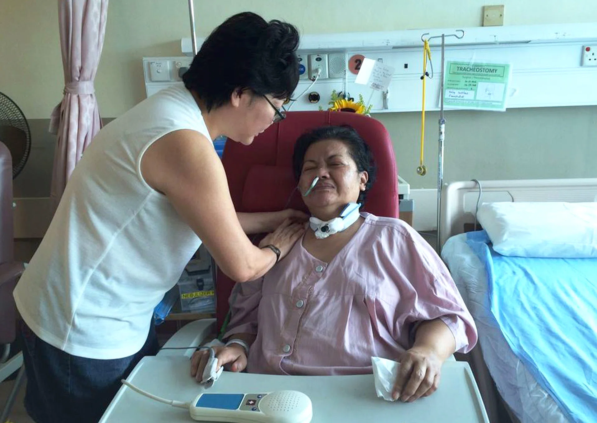 Madam Dora Sern praying with her domestic helper Felicidad Muna Mico, who has since moved to a normal ward.