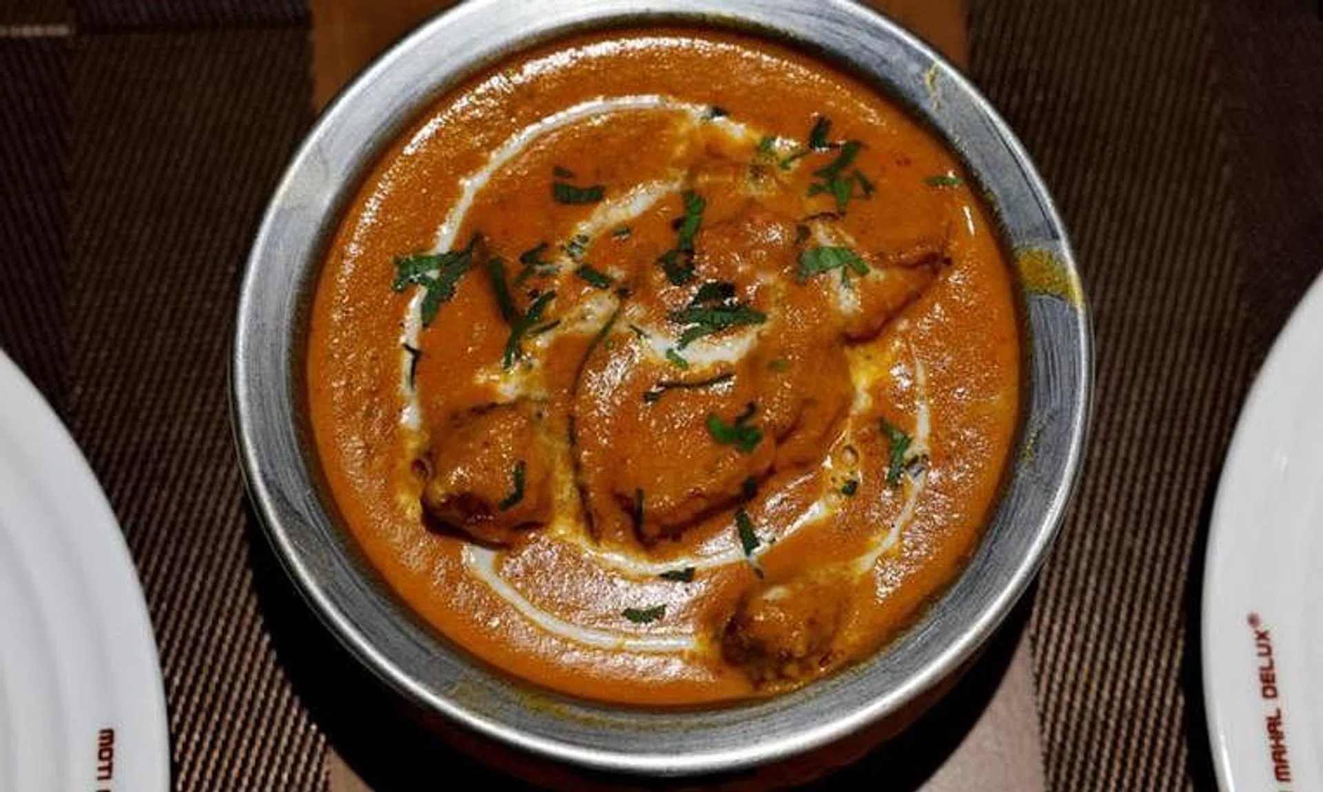A freshly prepared butter chicken dish is placed on a table inside the Moti Mahal Delux restaurant in New Delhi, India.