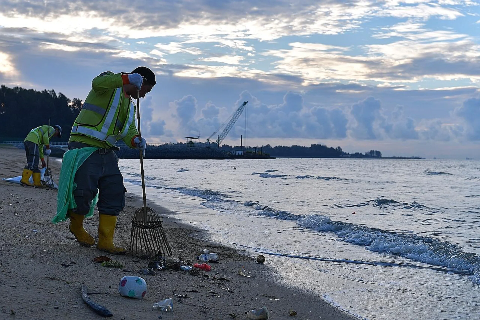 Workers start by clearing the flotsam washed highest ashore before moving lower, stopping at the point where they meet the tide. 