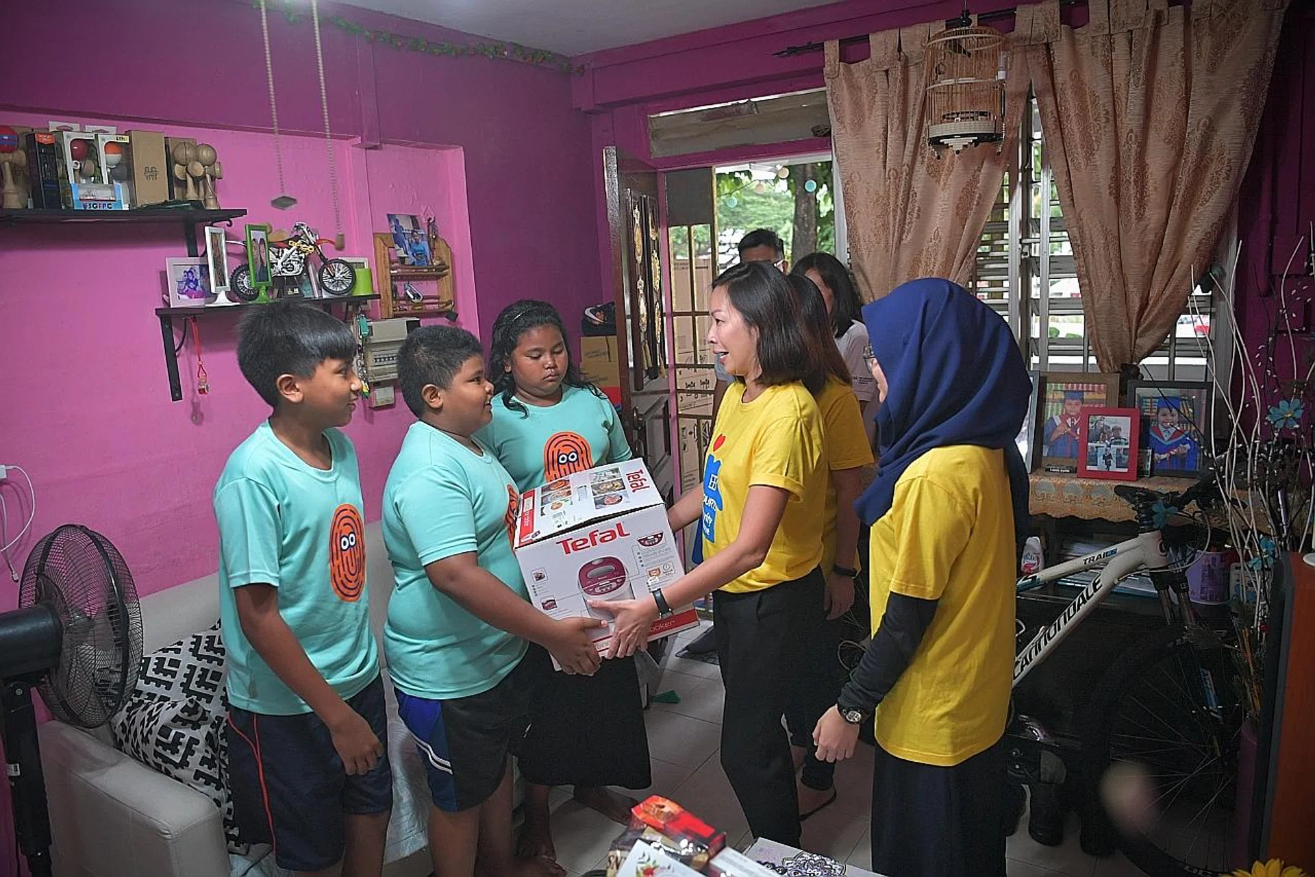 Courts Singapore marketing director Tammy Teo presenting a rice cooker and other items to Madam Ida Abdullah's children. 
