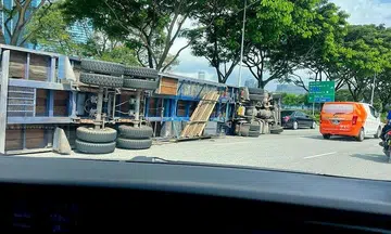 Trailer truck carrying concrete slabs tips over and lands on its side after accident in Sheares Avenue
