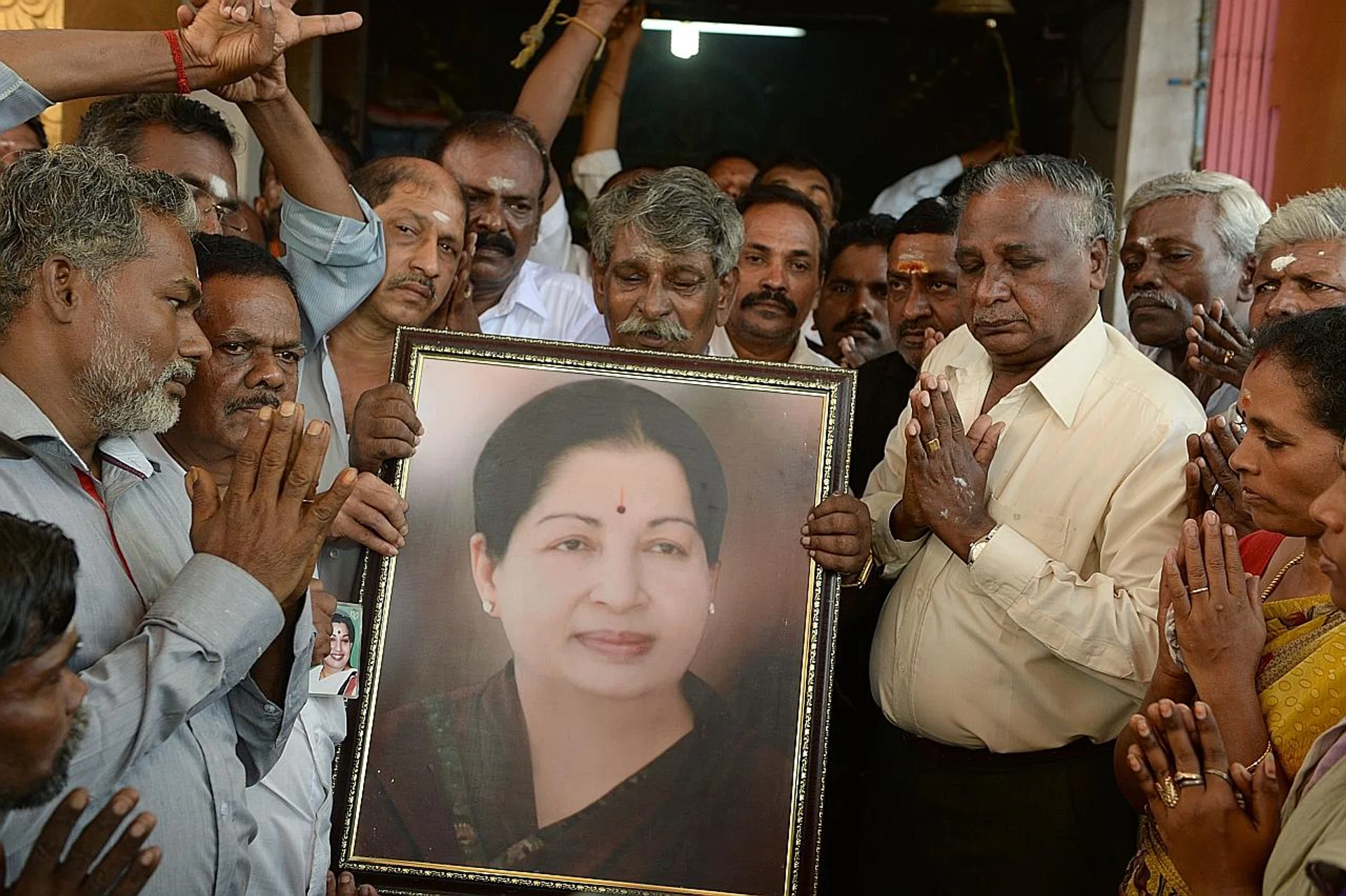 Supporters holding a photograph of Ms Jayalalithaa Jayaram as they offer prayers for her well-being at a temple in Mumbai on Monday. 