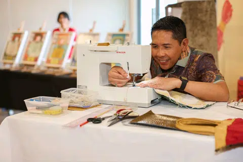 Second Minister for Education and Foreign Affairs Mohamad Maliki Osman sewing the finishing touches on his tote bag during the launch of the Our Tote-rific Community initiative.