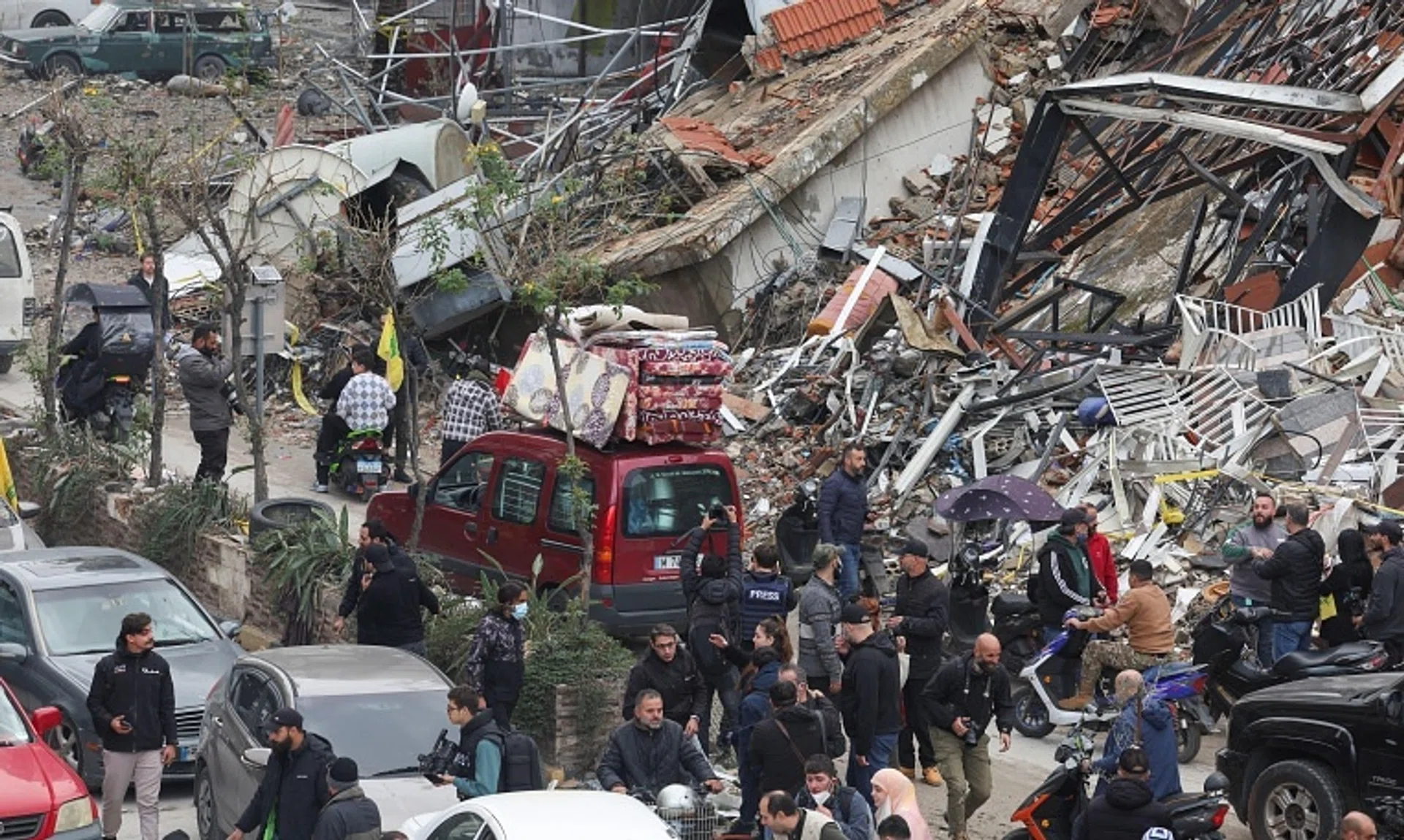 People gather as cars drive past rubble in Beirut after a ceasefire between Israel and Hezbollah took effect on Nov 27.