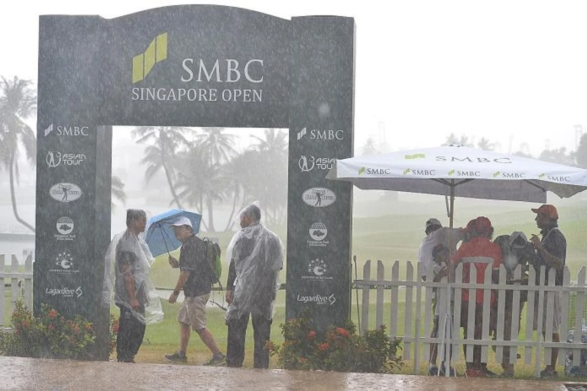 UNDERCOVER: Spectators and officials braving the rain at Serapong, as thunderstorms hit the tournament for the third time in four days.