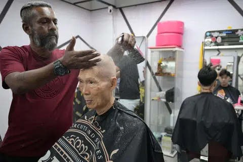 Barber Vishnu Vijendran cutting Mr Kwek Tee Nee's hair.