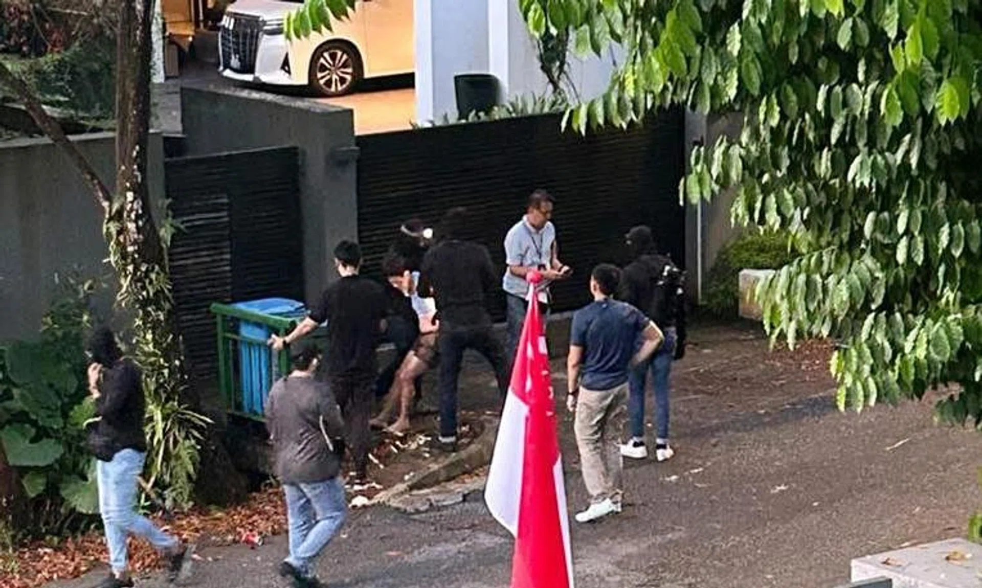 A man (in white shirt and shorts) being apprehended at 16 Ewart Park on Aug 15.