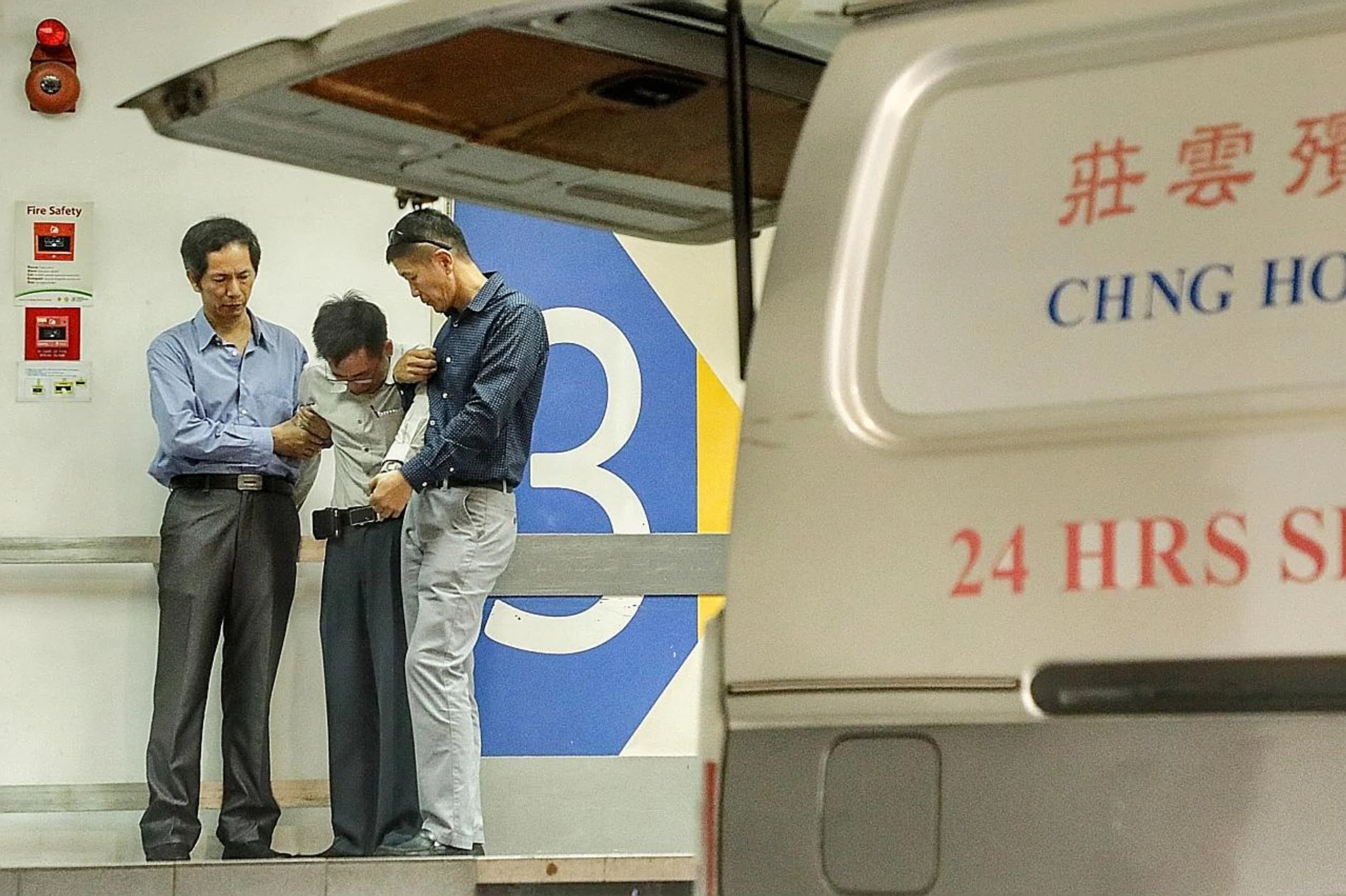 (Above) Mr Lin Xinjie's father being supported by his friends at the Singapore General Hospital mortuary. 