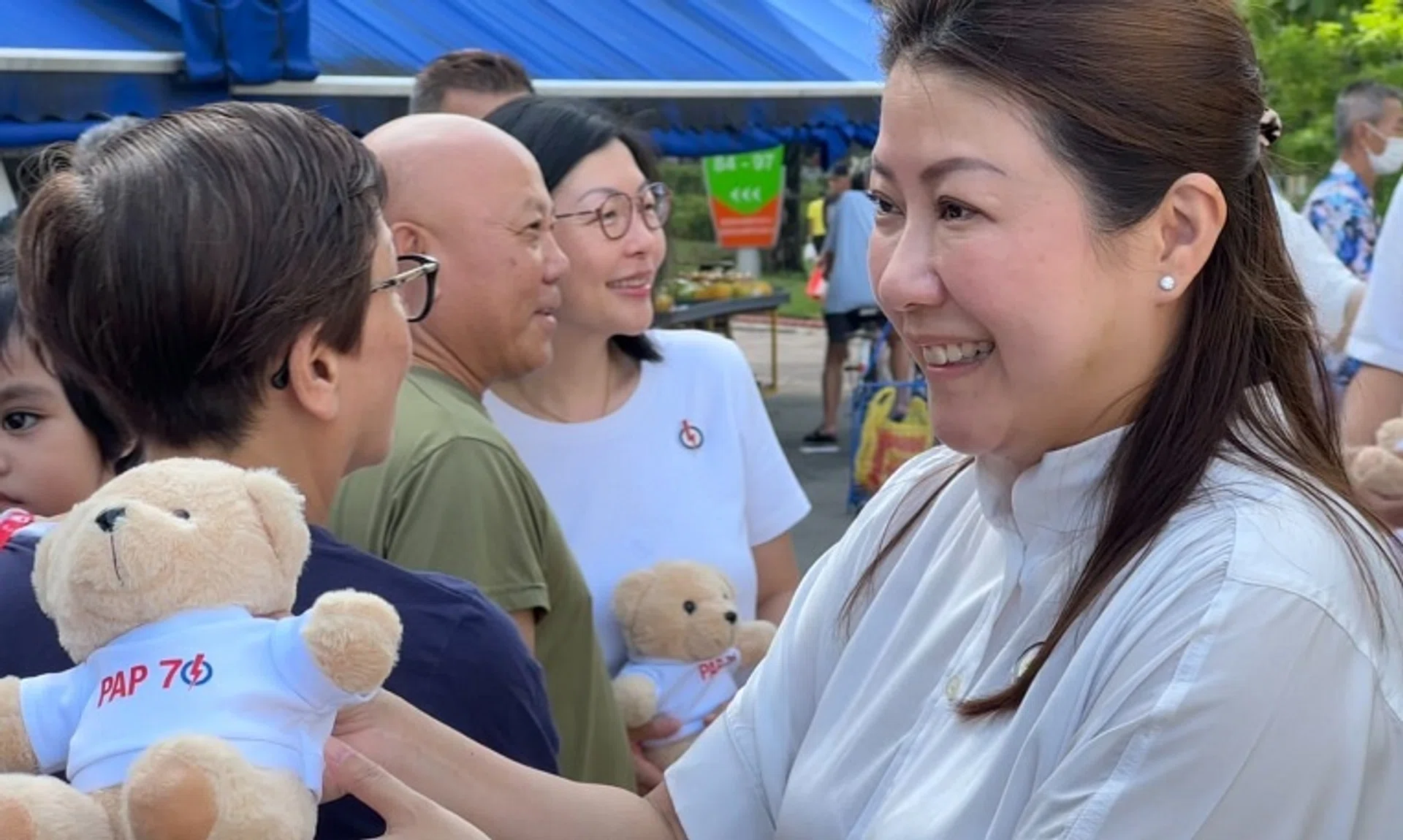Wah & Hua CEO Melissa Tan (right) giving out the PAP teddy bears at Bedok 85 Market with East Coast GRC MP Cheryl Chan (background, in white) on Nov 17.