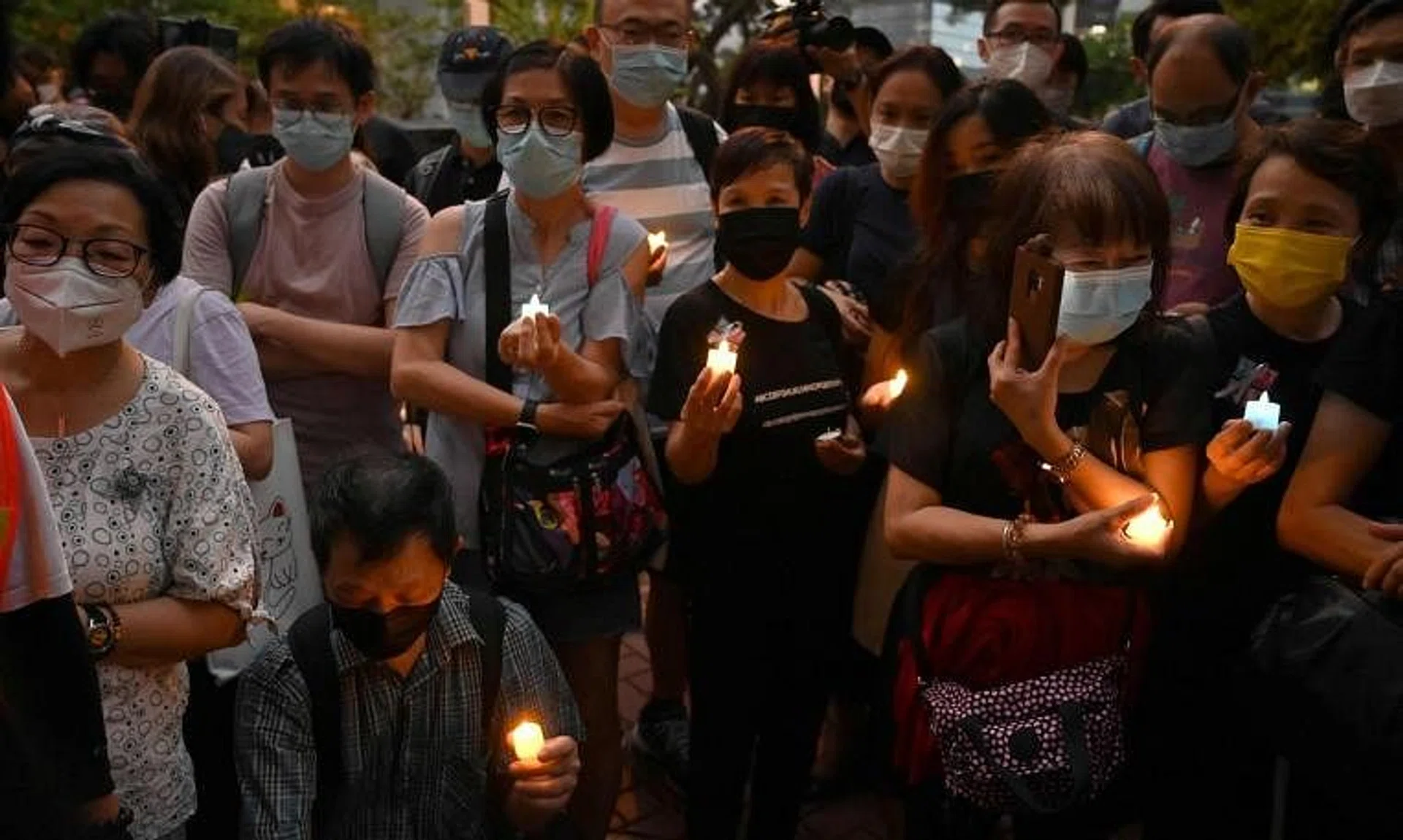 People hold candles as they gather outside the British Consulate in Hong Kong, on Sept 19, 2022.