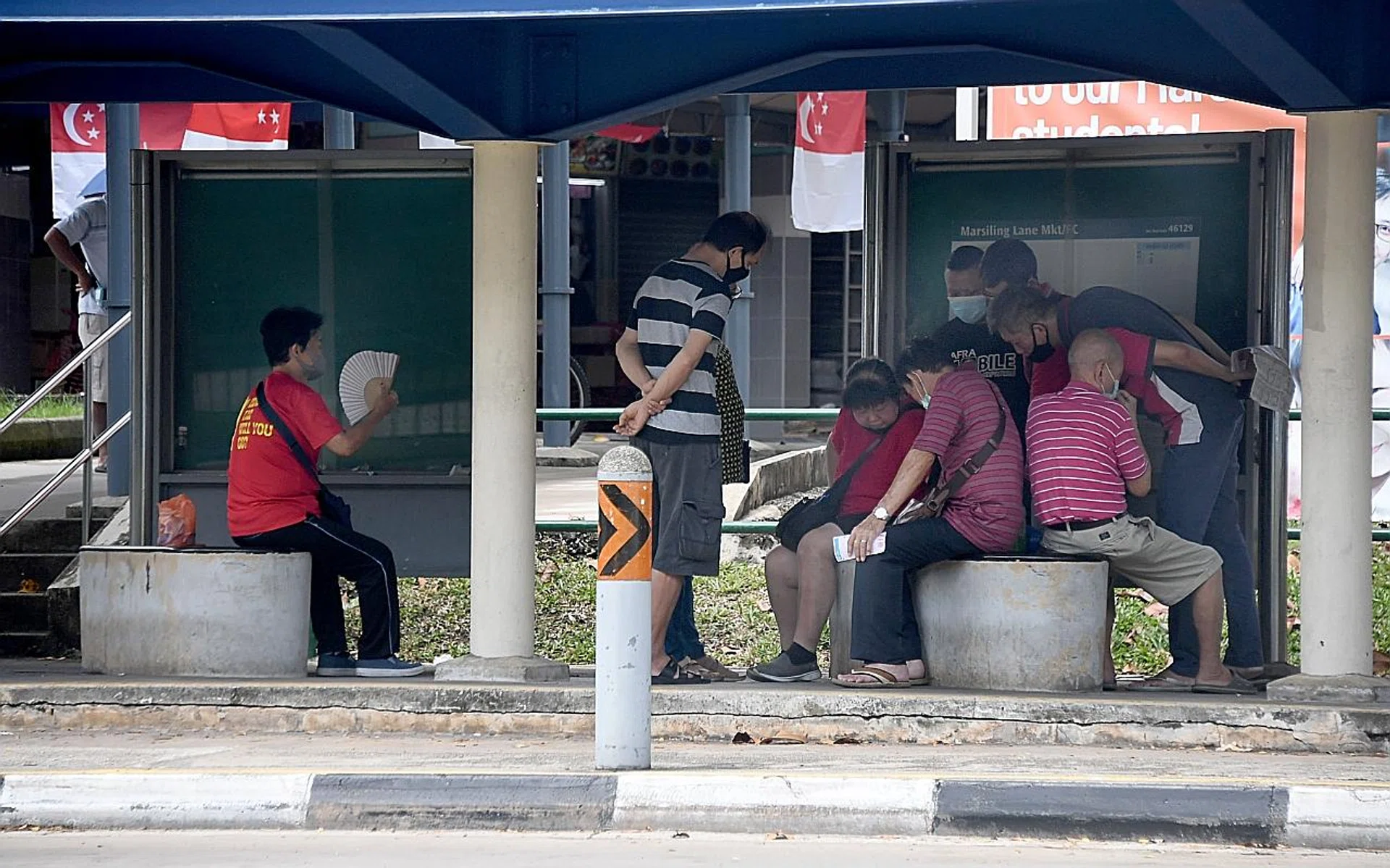Clusters of people, suspected to be openly gambling, were seen at a bus stop. 