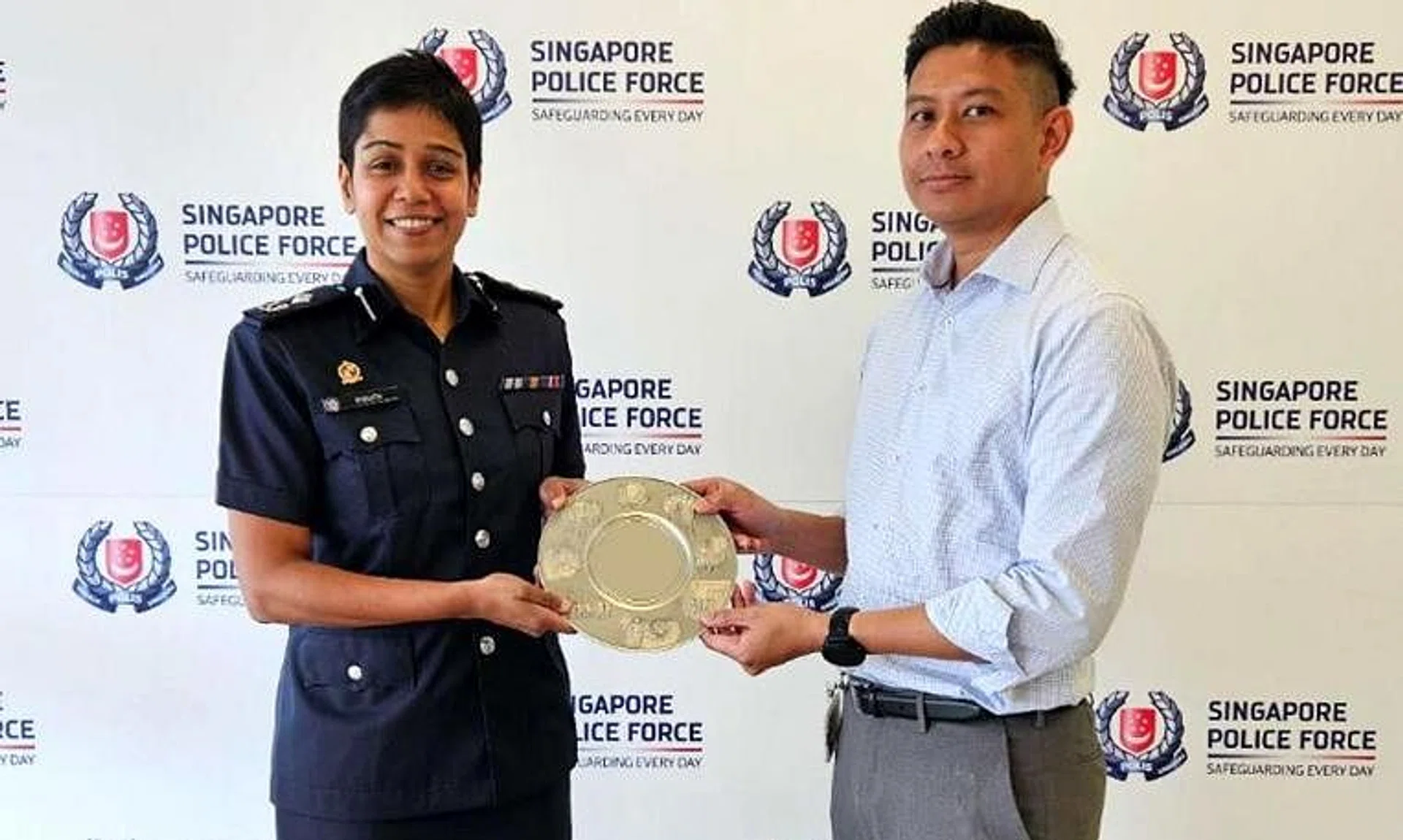 Commander Airport Police Division, Assistant Commissioner of Police M Malathi, presents the Public Spiritedness Award to Mr Helmi Ali.