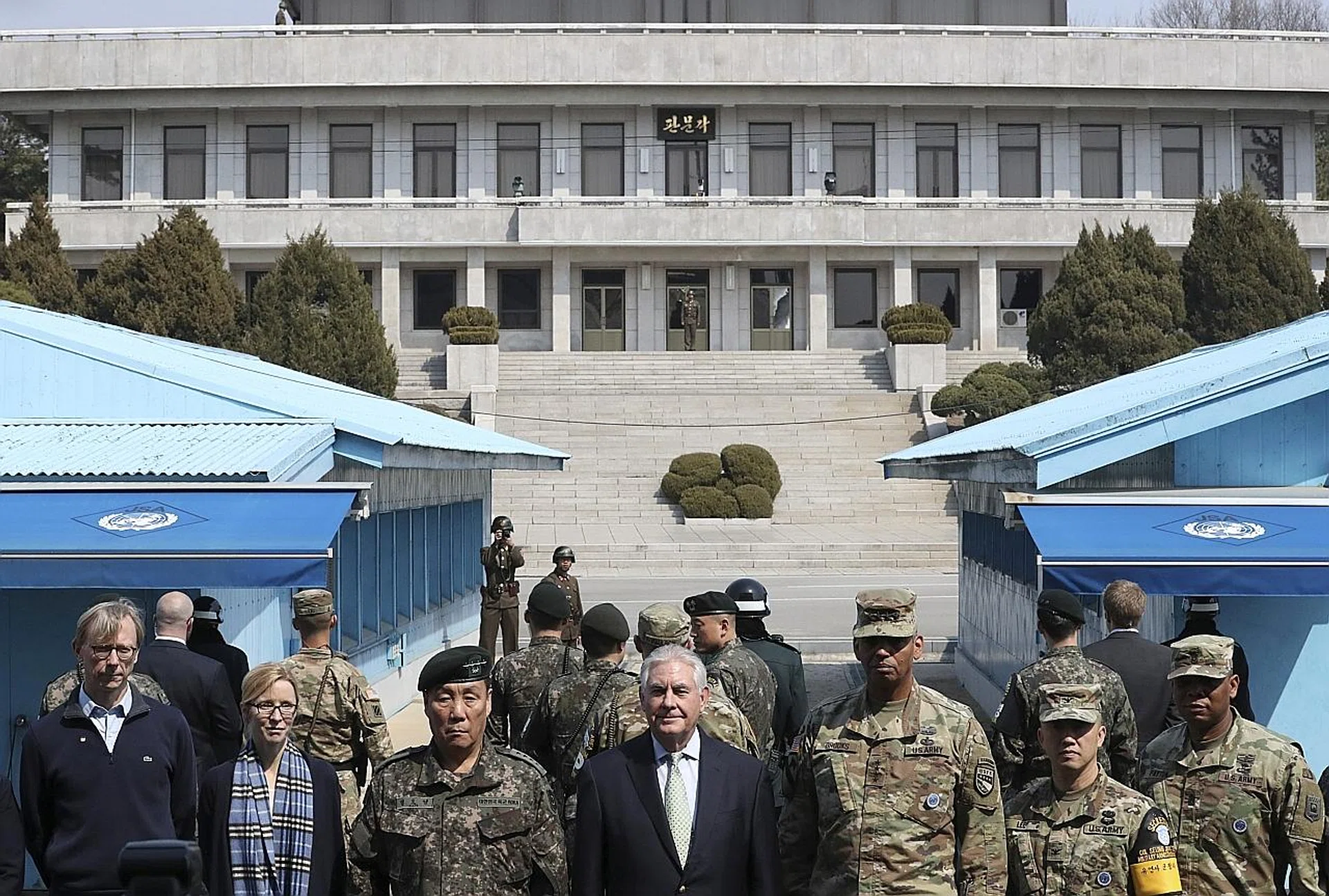 US Secretary of State Rex Tillerson (centre) standing with officers from the Combined Forces Command as North Korean soldiers look at the south side in the border village of Panmunjom, which separates the two Koreas. 
