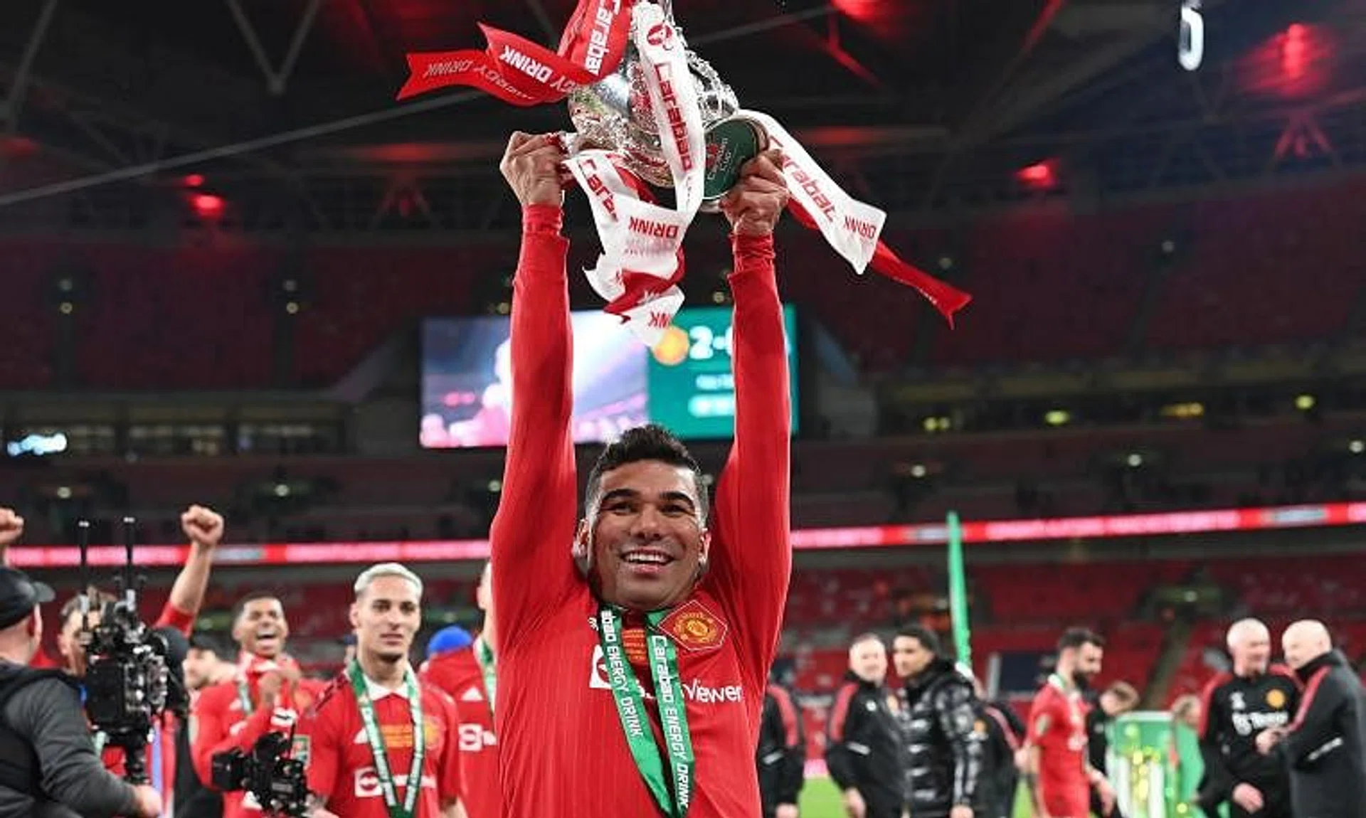 Manchester United's Brazilian midfielder Casemiro holds the trophy as Manchester United players celebrate their win.