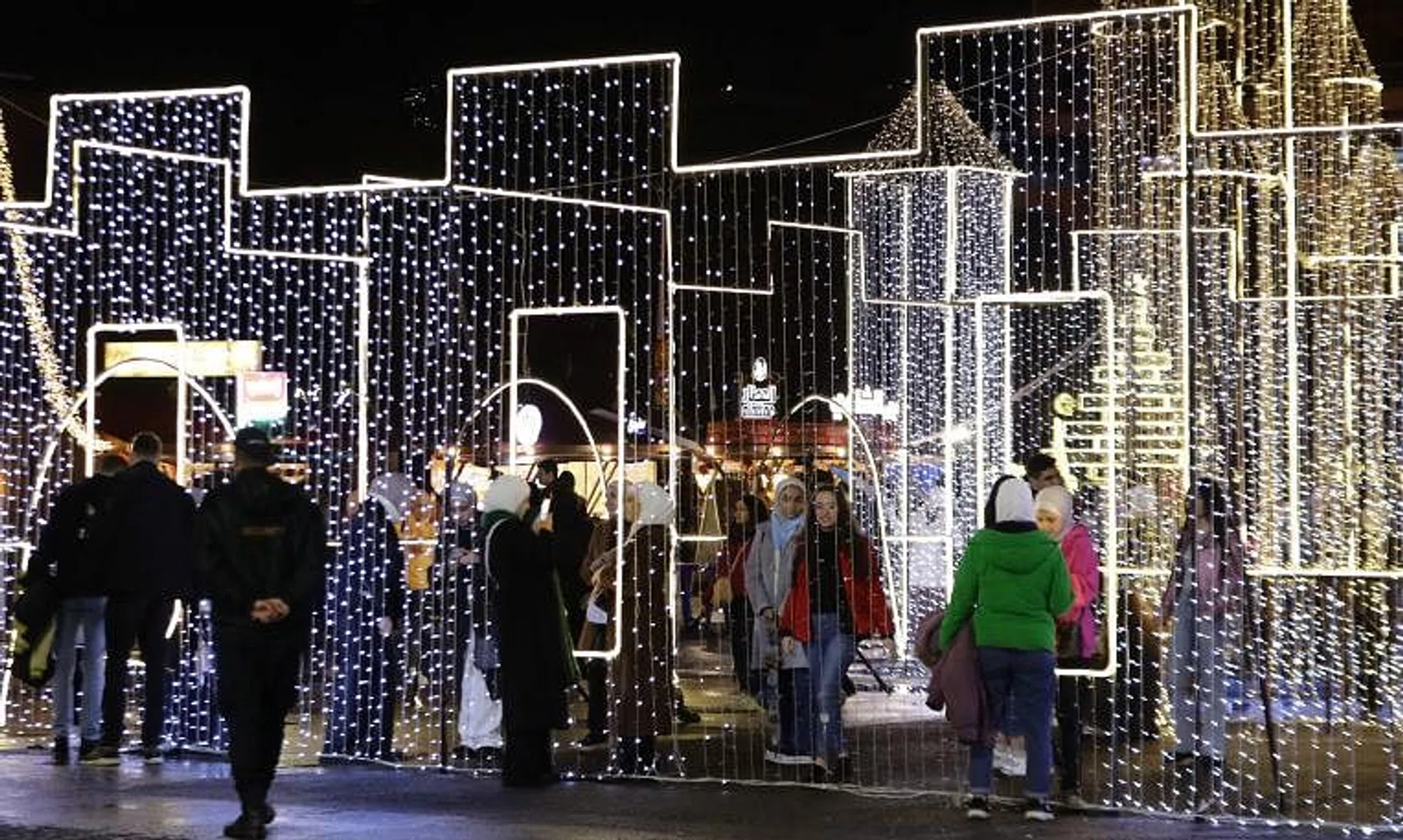 Syrians walk past Christmas decorations at a market in the capital Damascus on Dec 23, 2023.
