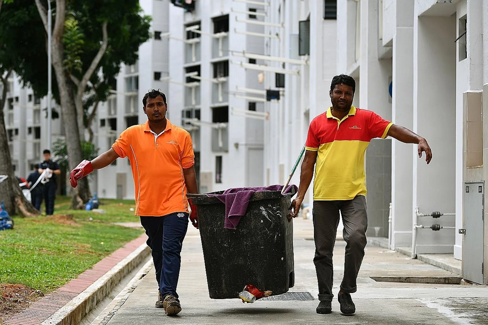 Mr Patwari Shamin (left) and his colleague carrying the rubbish chute bin to the bin centre on Tuesday after it had been checked. A baby boy was found alive in the bin at the bottom of a rubbish chute at Block 534 Bedok North Street 3 that morning. 