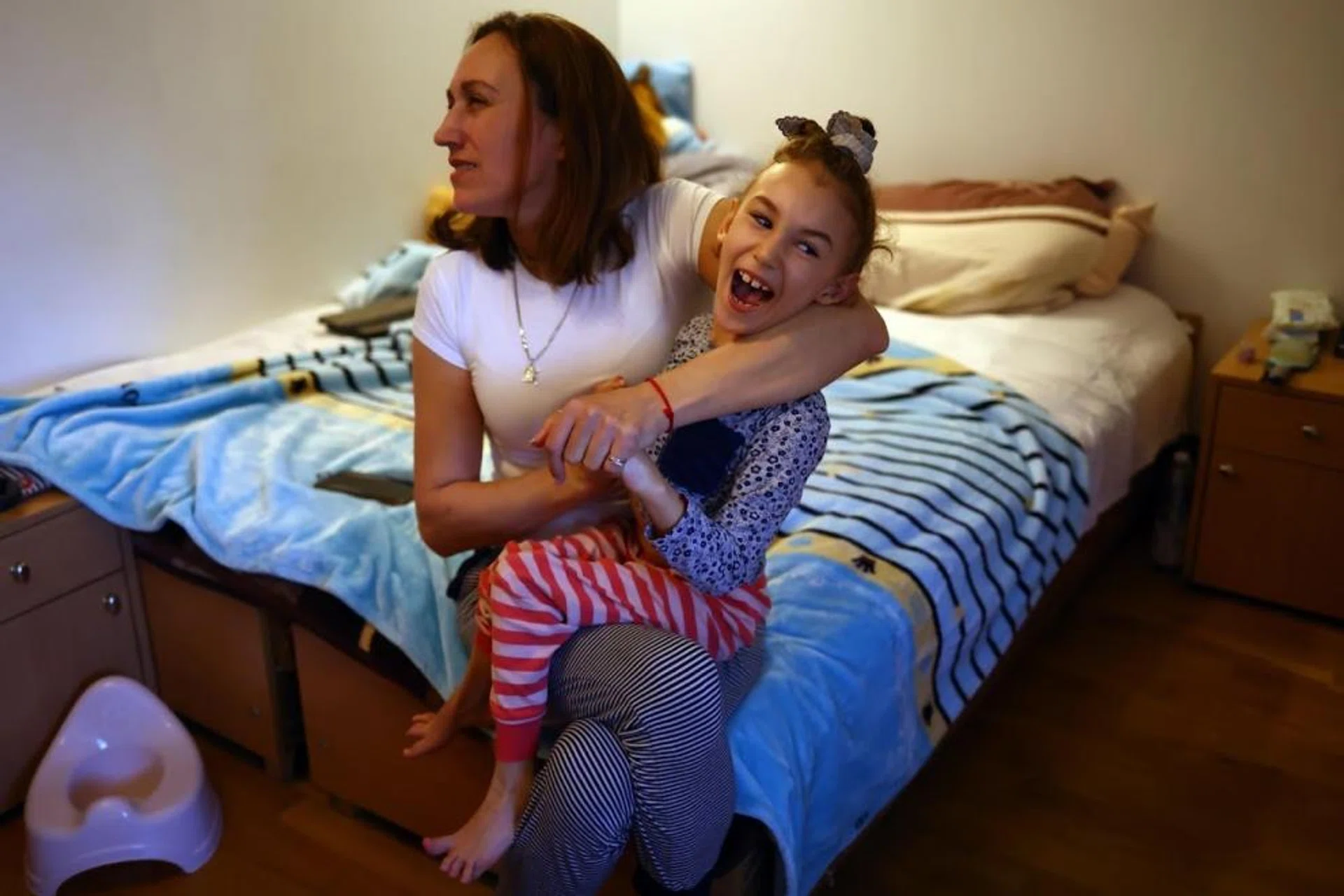 Ukrainian refugee Alexandra Zhuravel, 38, holds her daughter Alevtina Bravorichenko-Crane, 8, in their bedroom at the Benedictine Sisters Monastery, which has welcomed refugees amid Russia's invasion of Ukraine, in Jaroslaw, Poland, March 22, 2022.