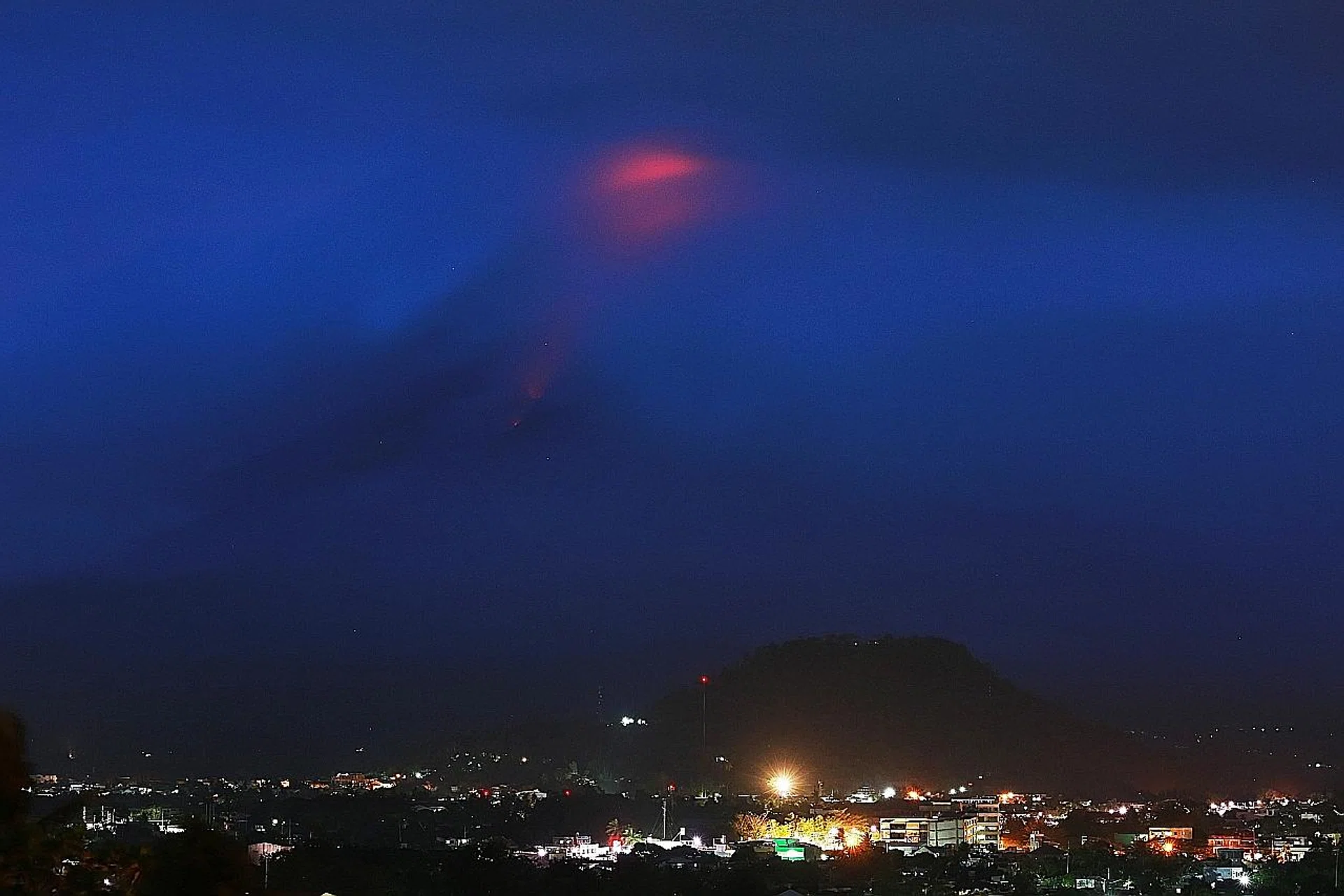 The glow (at top) of lava from the cloud-covered Mayon volcano yesterday. 