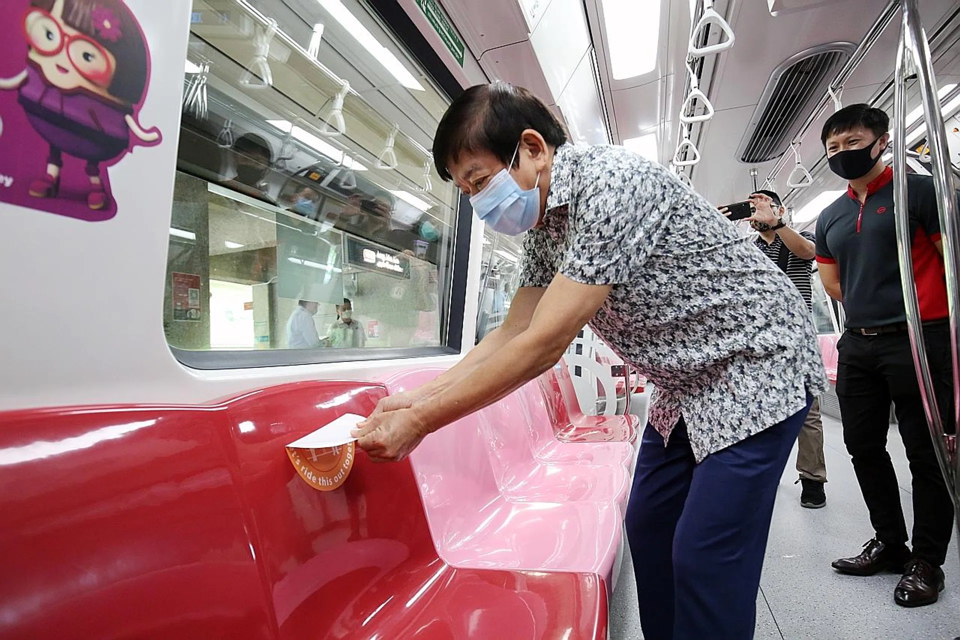 Mr Khaw Boon Wan removing a social distancing sticker from an MRT train seat yesterday as physical distancing will be tough once the crowds return. 