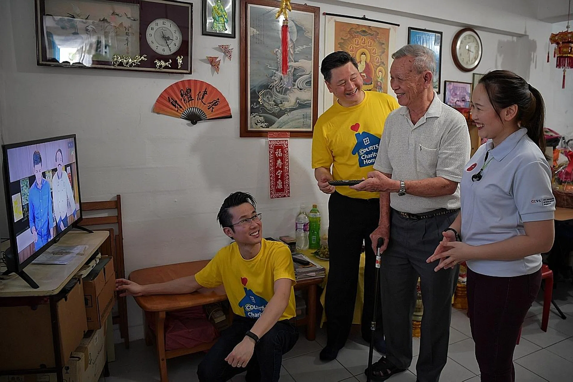 Mr Ben Tan, country CEO of Courts Singapore (second from left) showing Mr Ng Ah Ngow (third from left) the functions of the new TV. 