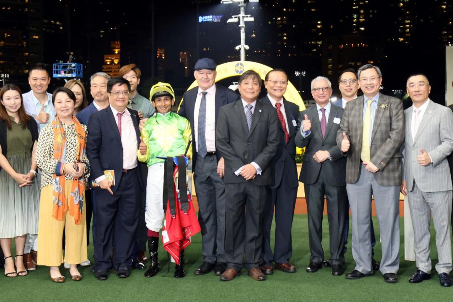 The Singapore Pools delegation of chief product officer Simon Leong (centre, in grey striped tie), board member Tan Choon Shian (red tie), chairman Kaikhushru S. Nargolwala (light purple tie) and product planning and development senior manager Eric Loh (standing behind) posing with the connections of Singapore Pools Handicap winner Tomodachi Kokoroe at Happy Valley. Beside Leong are trainer David Hayes and jockey Karis Teetan.