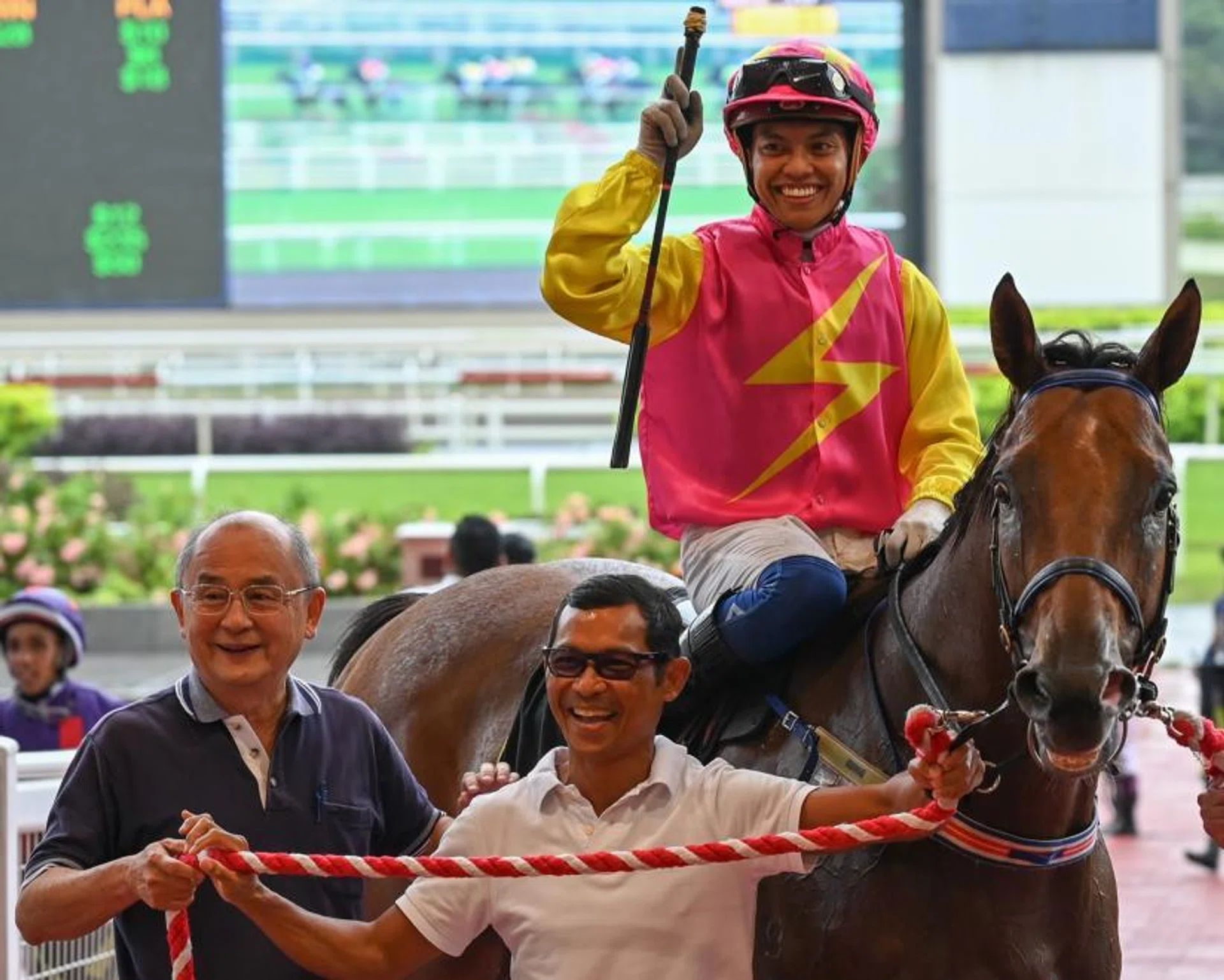 Stephen Gray's assistant trainer Saimee Jumaat is all smiles as he leads in Silent Is Gold and Jamil Sarwi at the winner's circle after the running of the Class 1 1,200m race on Jan 20.