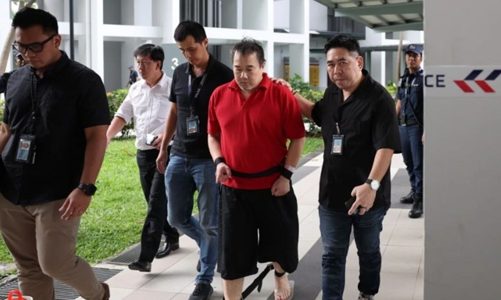 Toh Chee Hong (in red), 50, being led by the police back to the crime scene in Clementi on Oct 28.