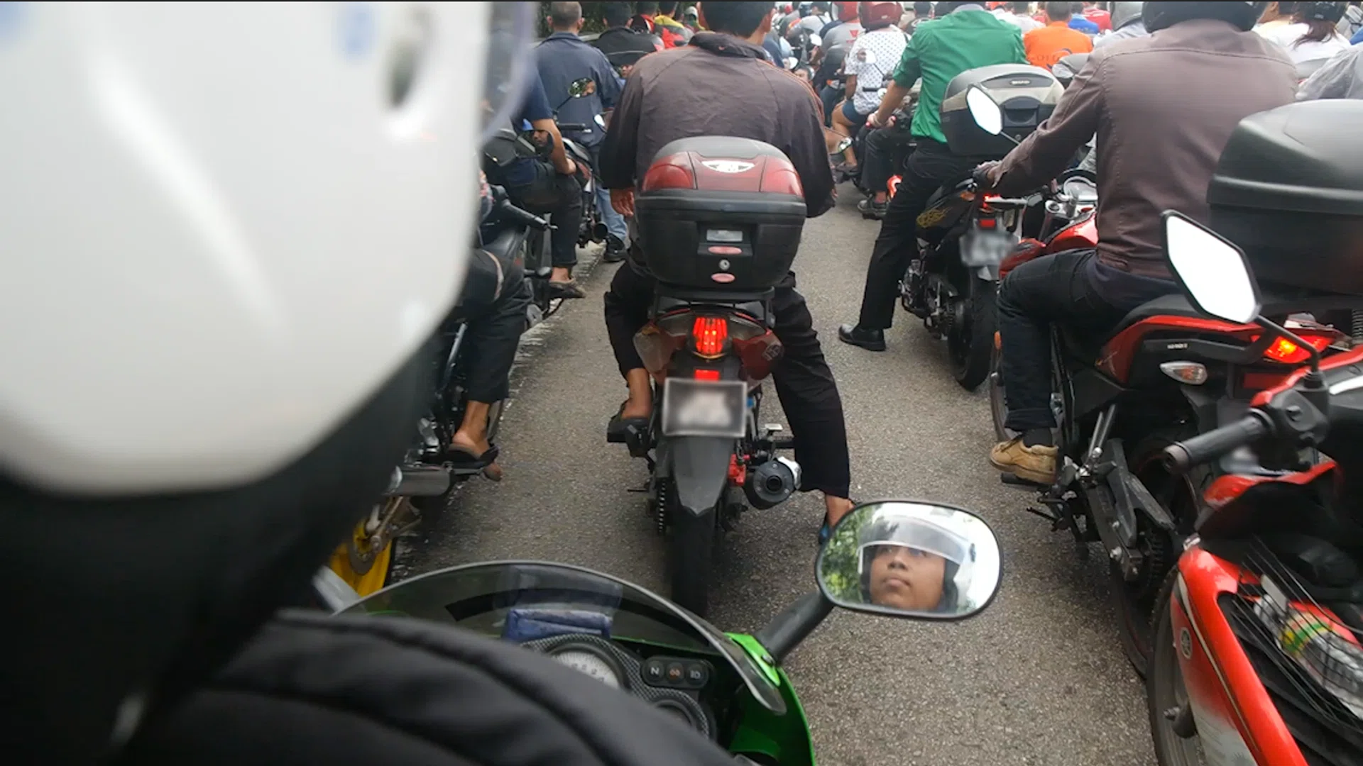 Ngee Ann Polytechnics student Muhammad Fareez Buhari (reflected in the motorcycle mirror) has to endure the long wait on the causeway to travel back to his home in Johor Baru to break fast.