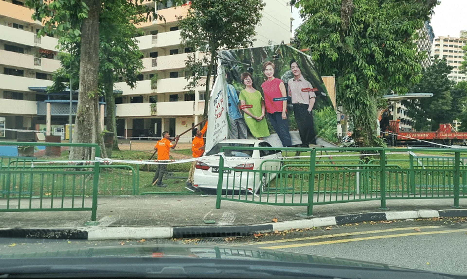 A photo showed a white car which had crashed into the railings of a pavement and landed on a grass patch near a basketball court.