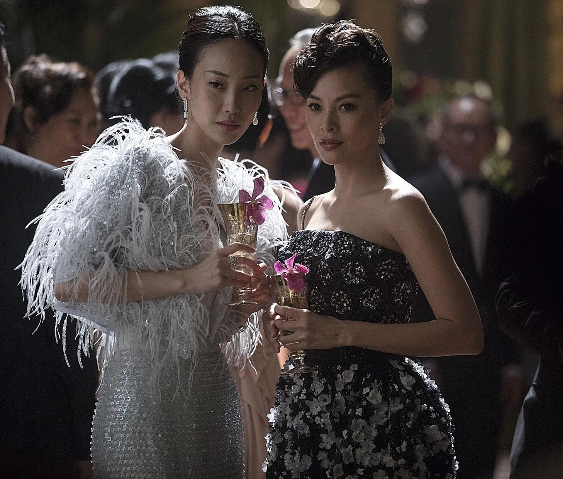 Constance Lau (left, in a Ralph & Russo gown) with Carmen Soo in Crazy Rich Asians. 